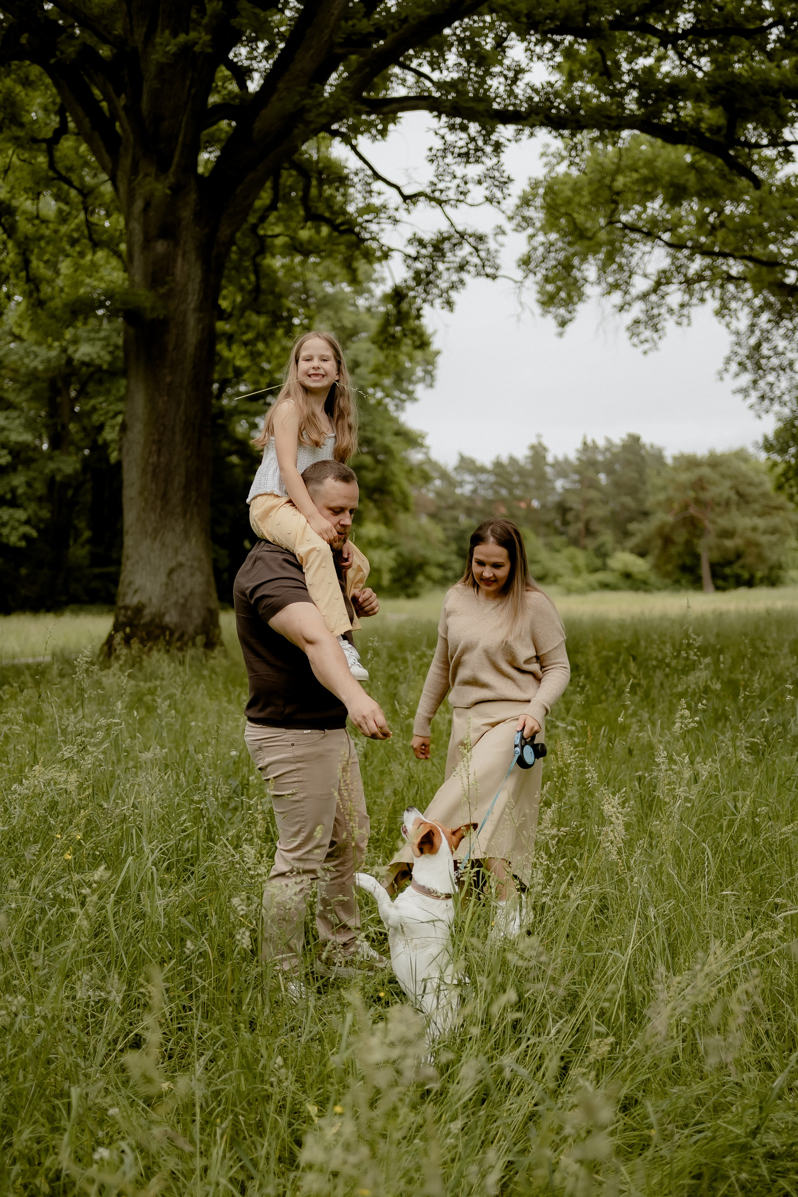 Eltern spazieren mit ihrer Tochter und dem Familienhund über eine Wiese in Nürnberg-Eibach.
