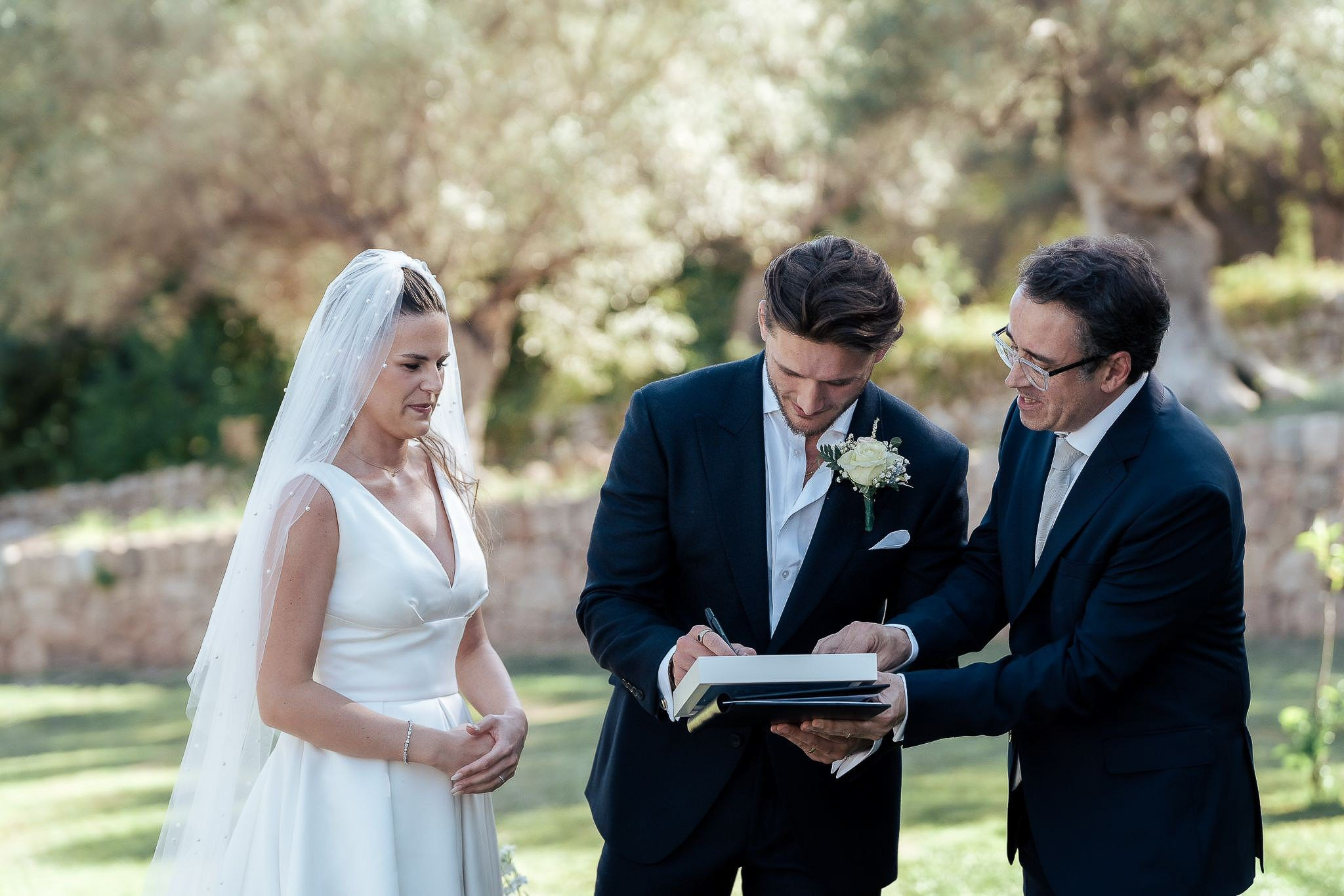 Close-up of bride and groom signing the register during their destination wedding ceremony