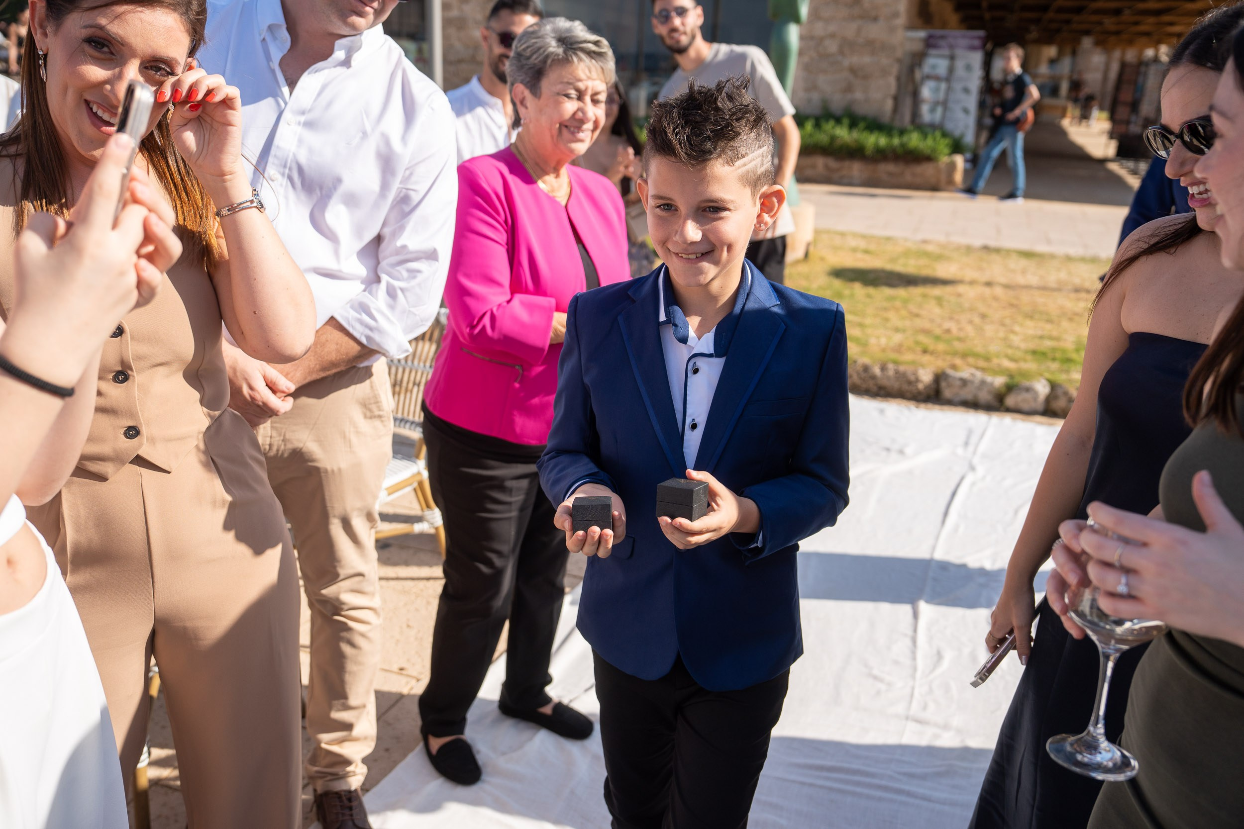 A young ring bearer holds the wedding rings before the ceremony