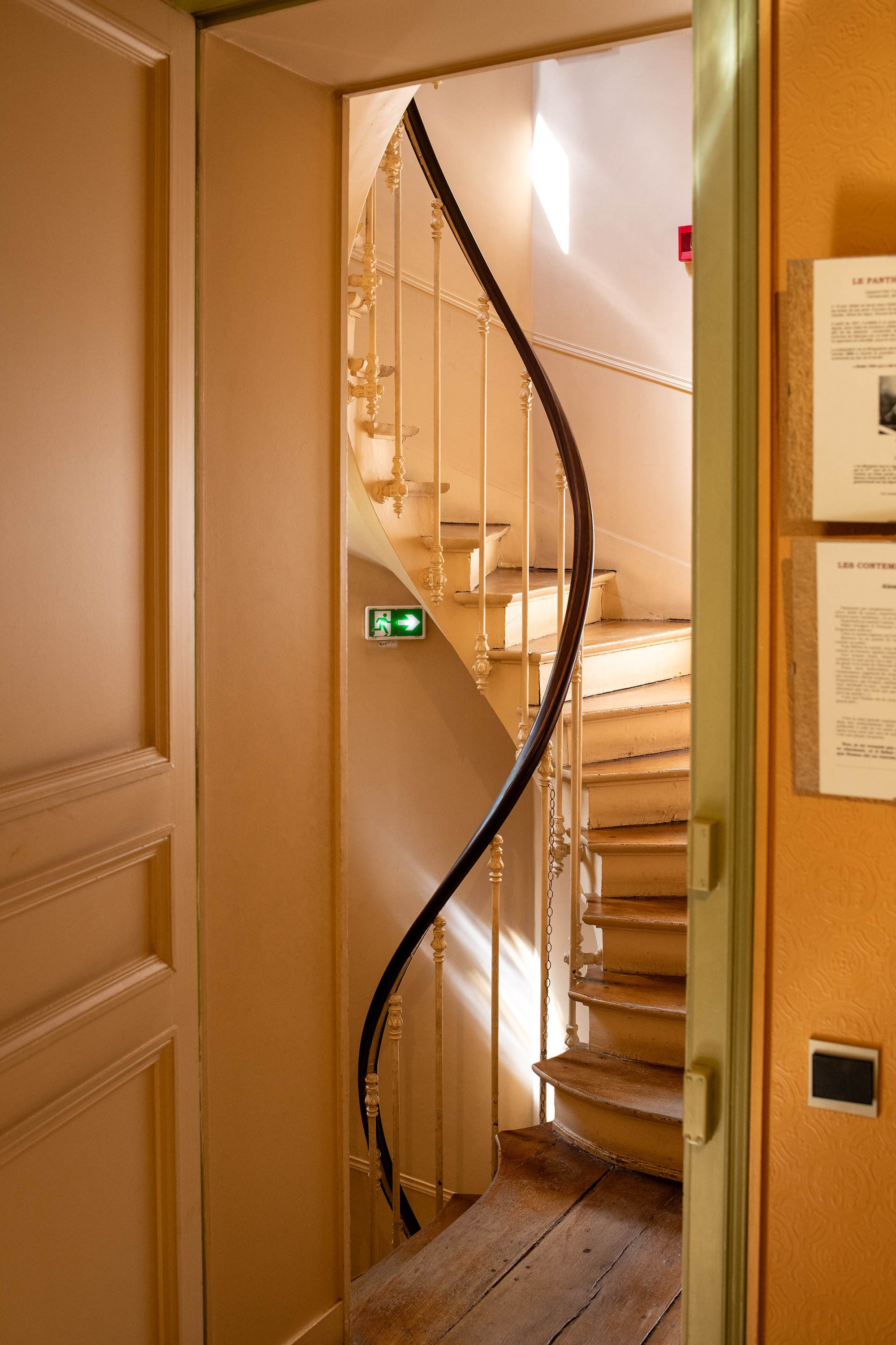 Curved wooden staircase with decorative iron railing inside the Château de Monte-Cristo museum in France.