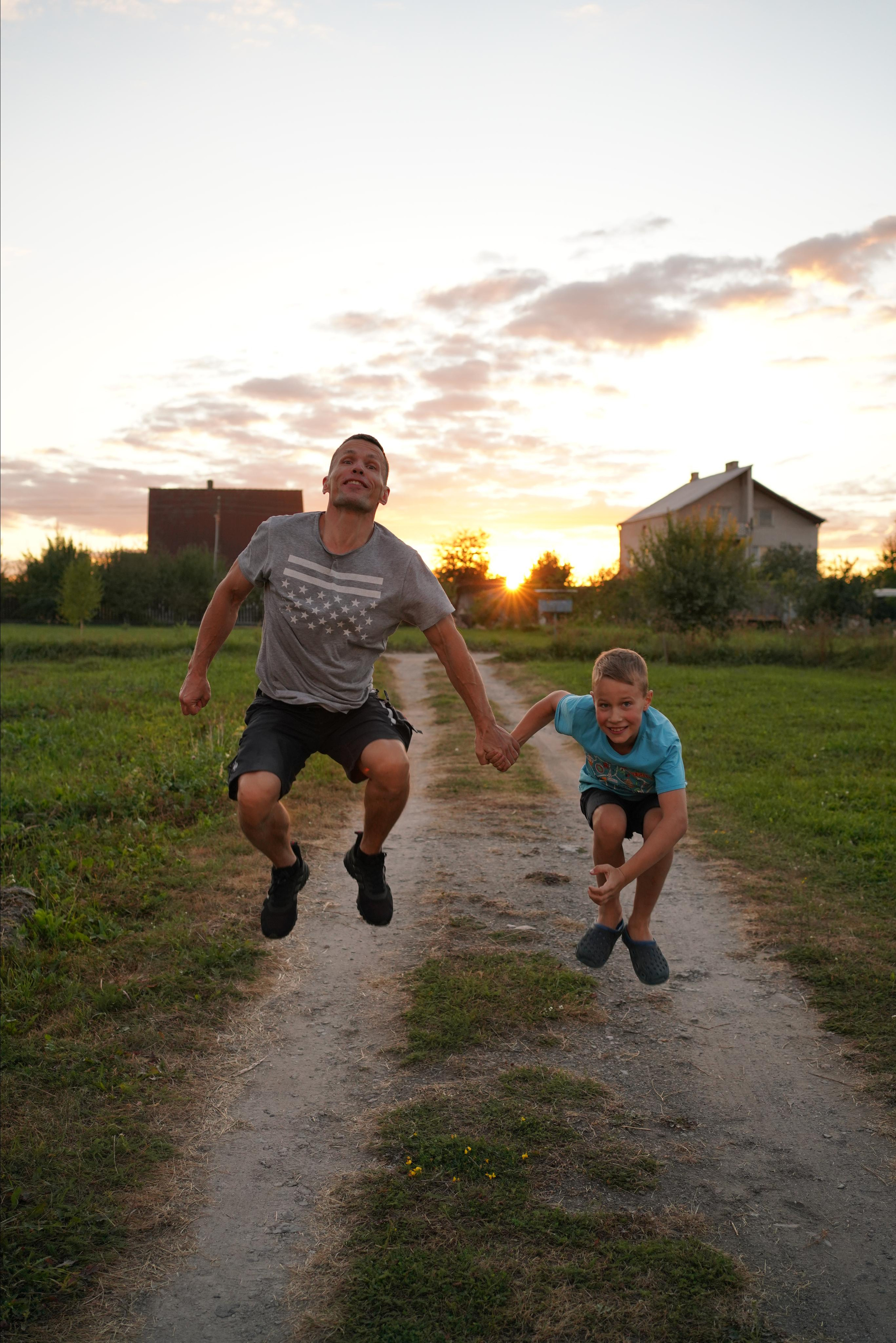 Vater und Sohn springen hoch  im Sonnenuntergang