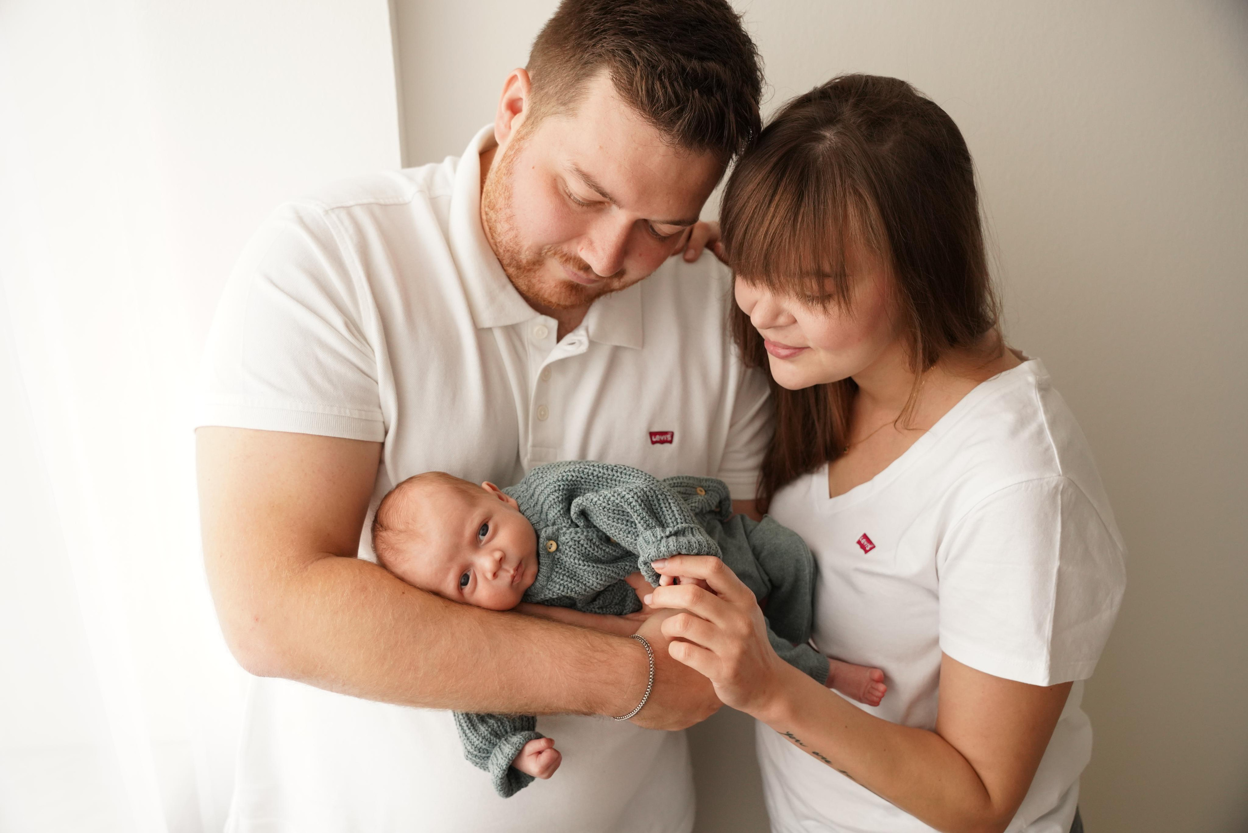 Eltern halten ihr Baby im Arm und bewundern es