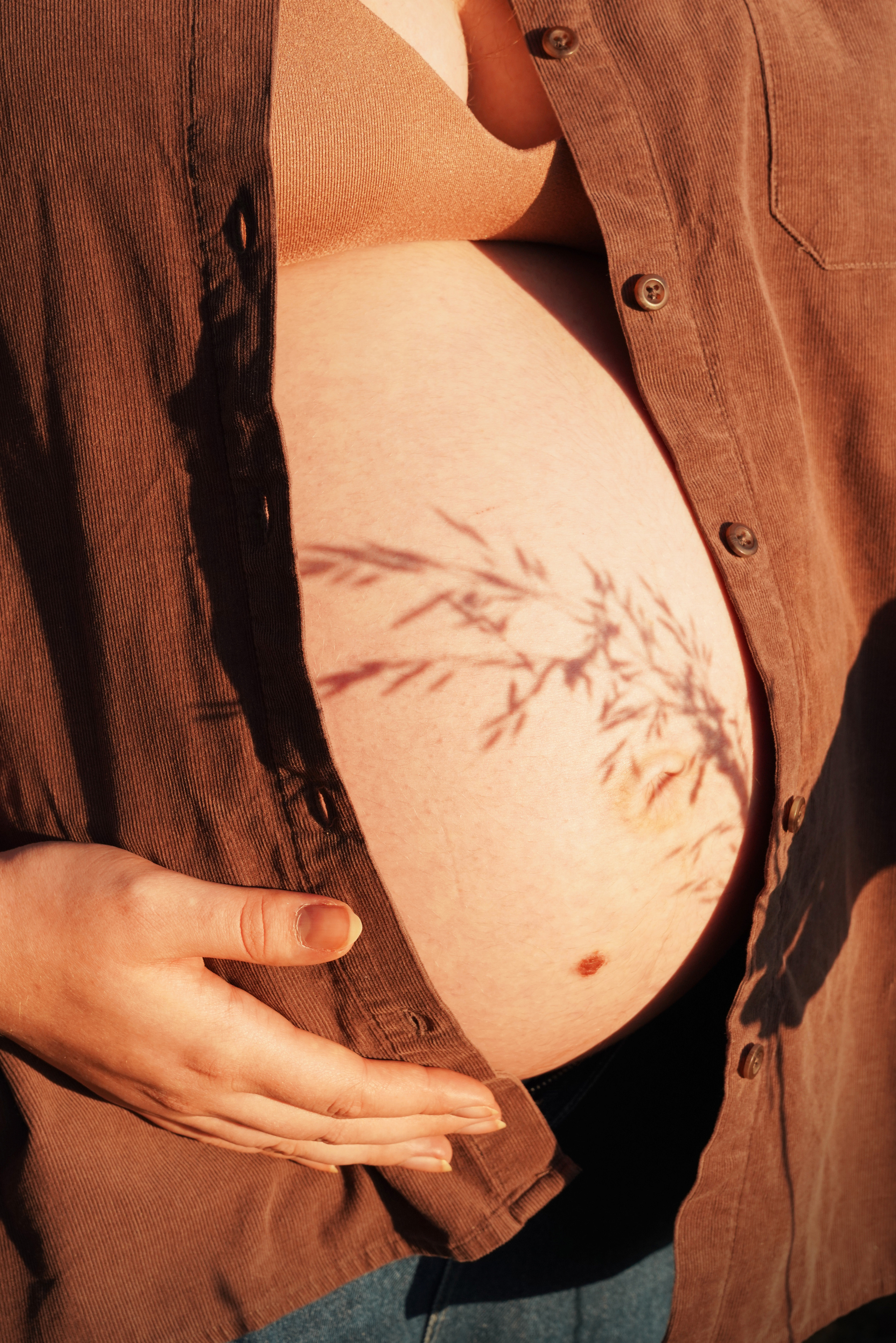 Schatten einer Blume auf dem Bauch einer schwangeren Frau