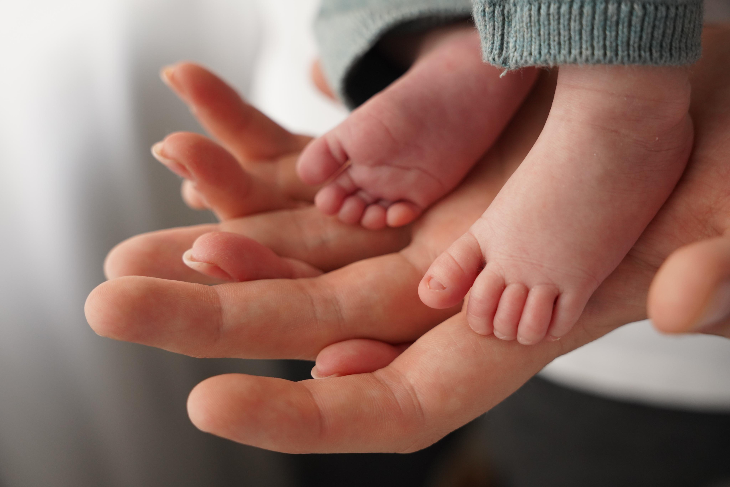 Der kleine Fuß eines Jungen in den Händen der Eltern