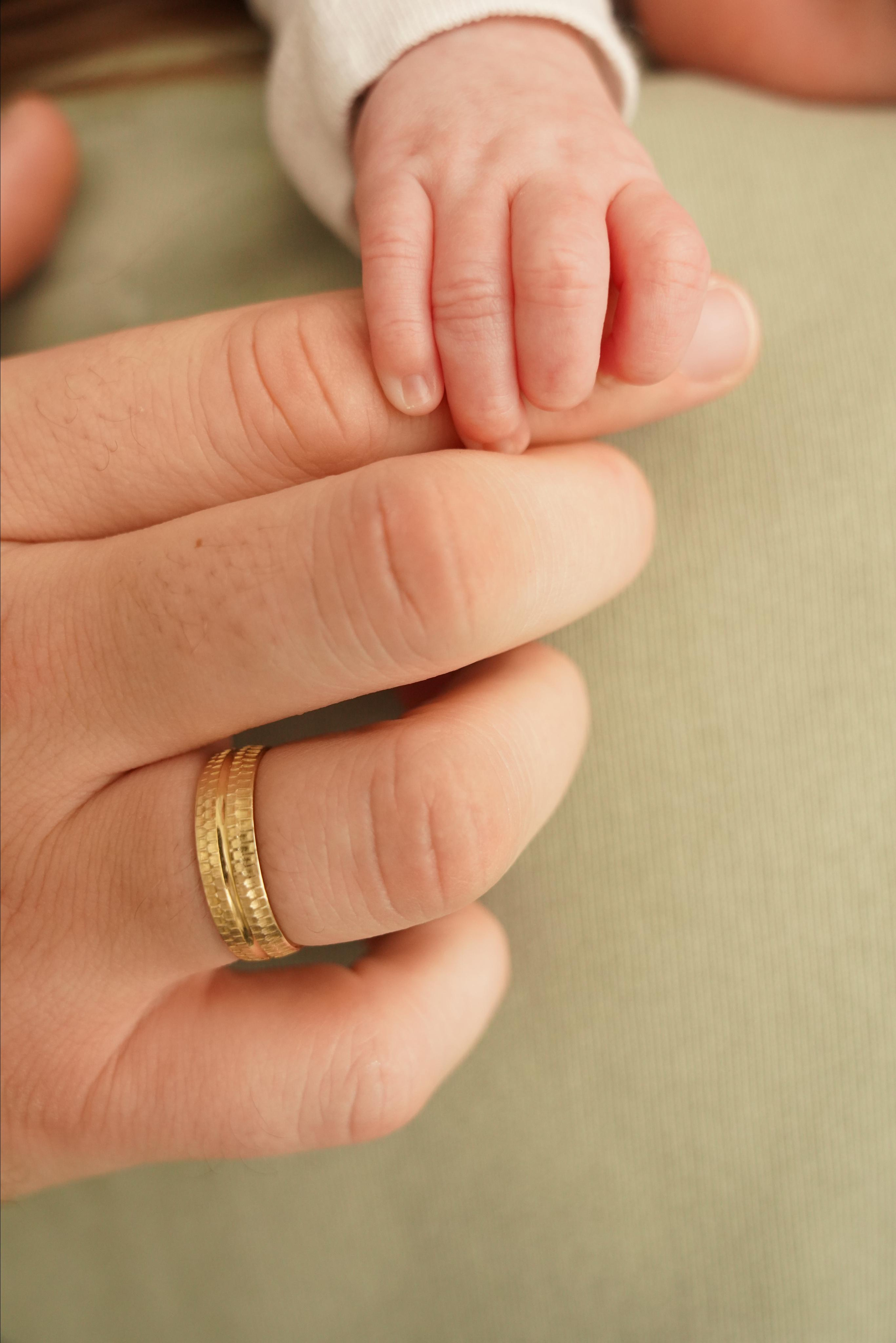 Die Hände der Mutter halten den Finger des Neugeborenen