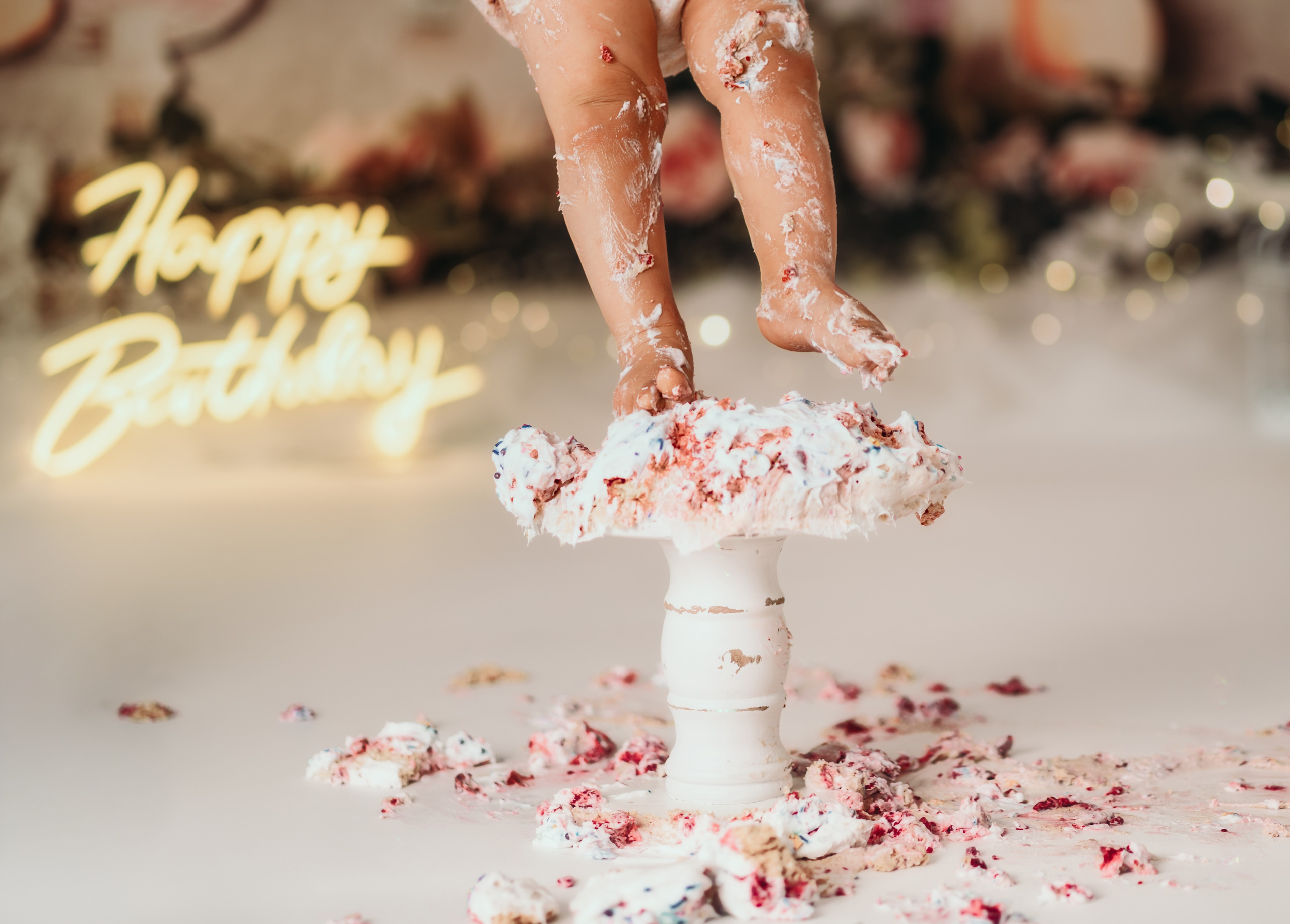 Beba sedi pored torte tokom cake smash fotografisanja u roze temi