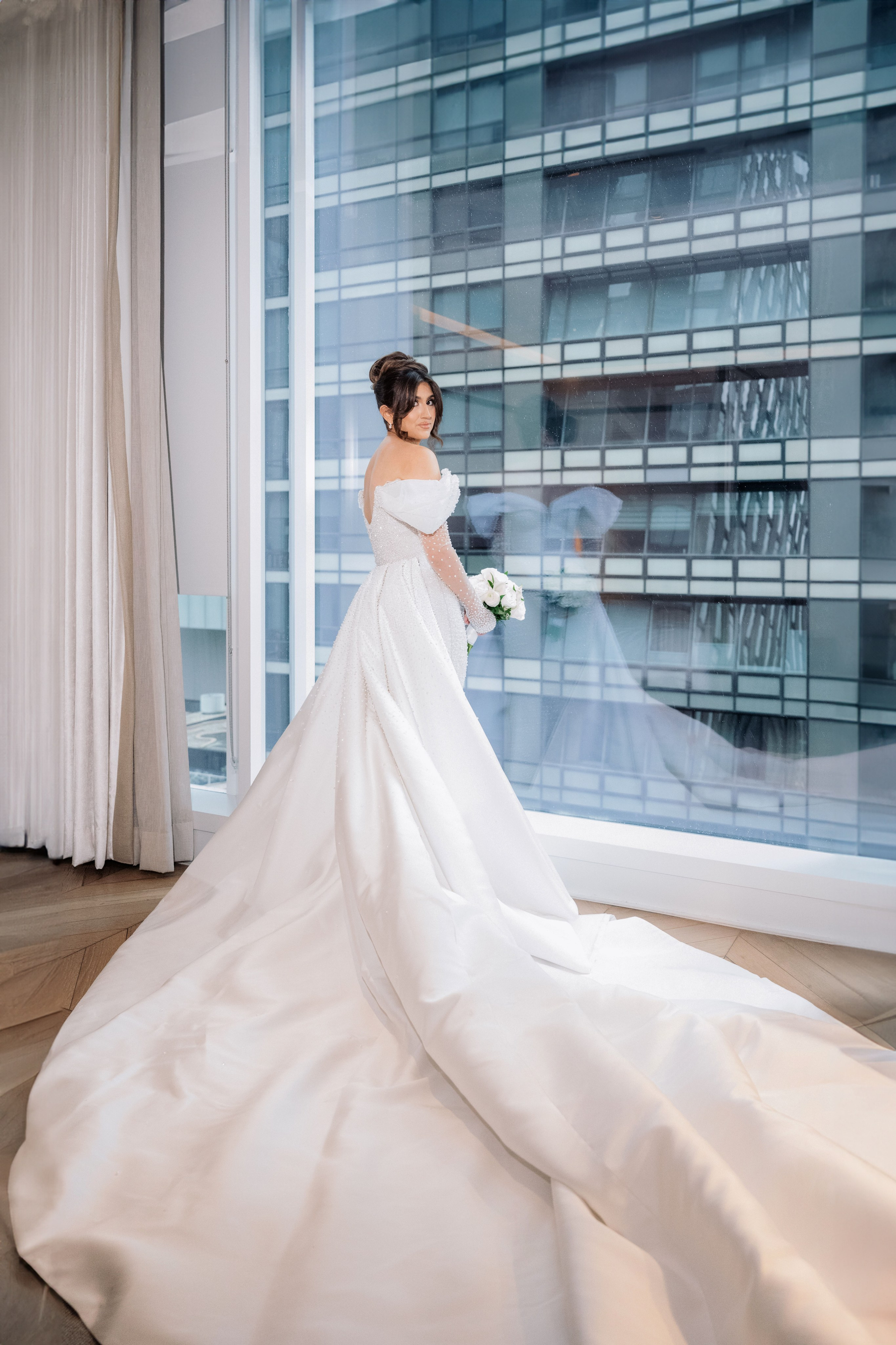 a bride in a white wedding dress standing in front of a window