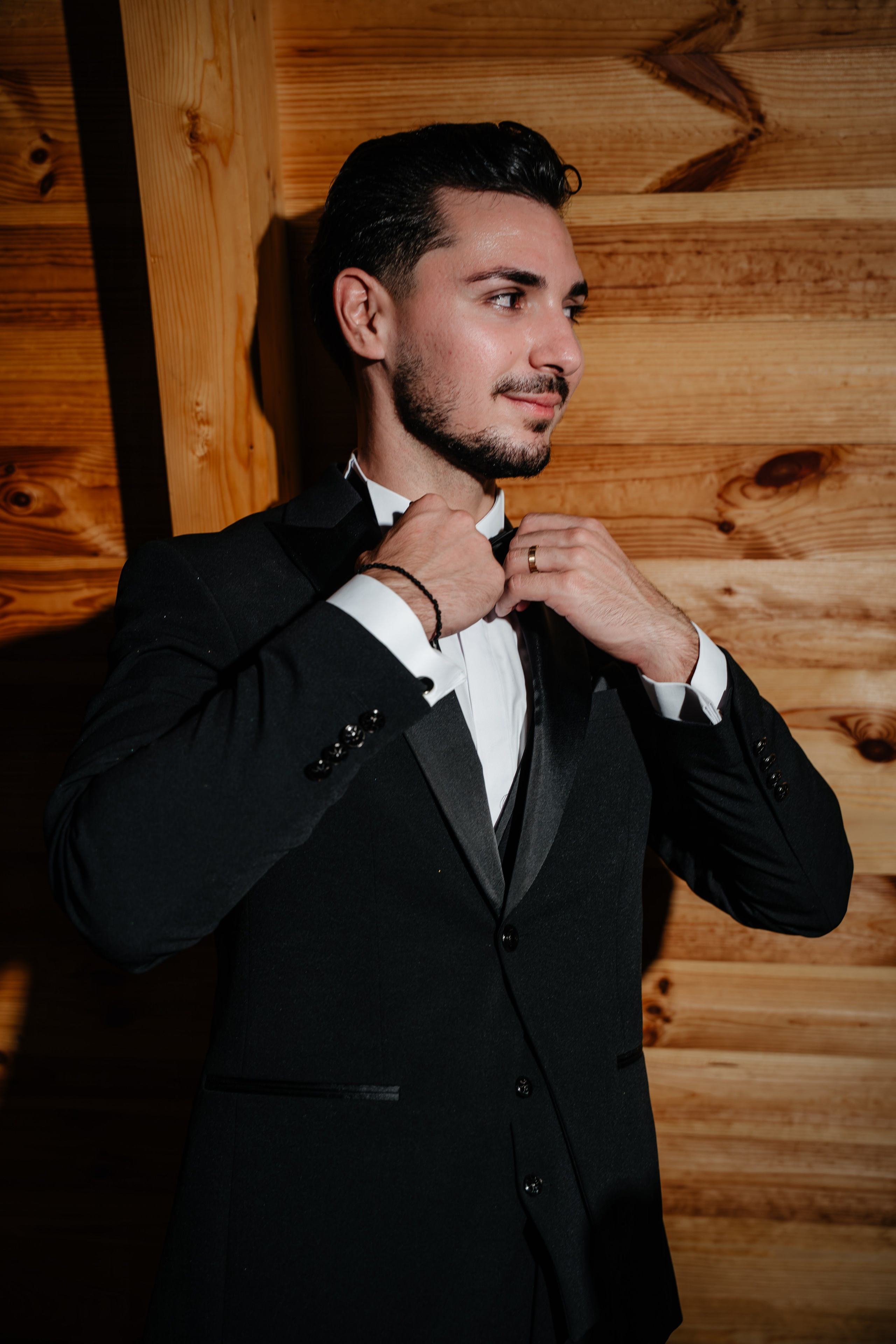 Portret de mire ajustându-și papionul în interiorul modern de la Cabana Masiv.