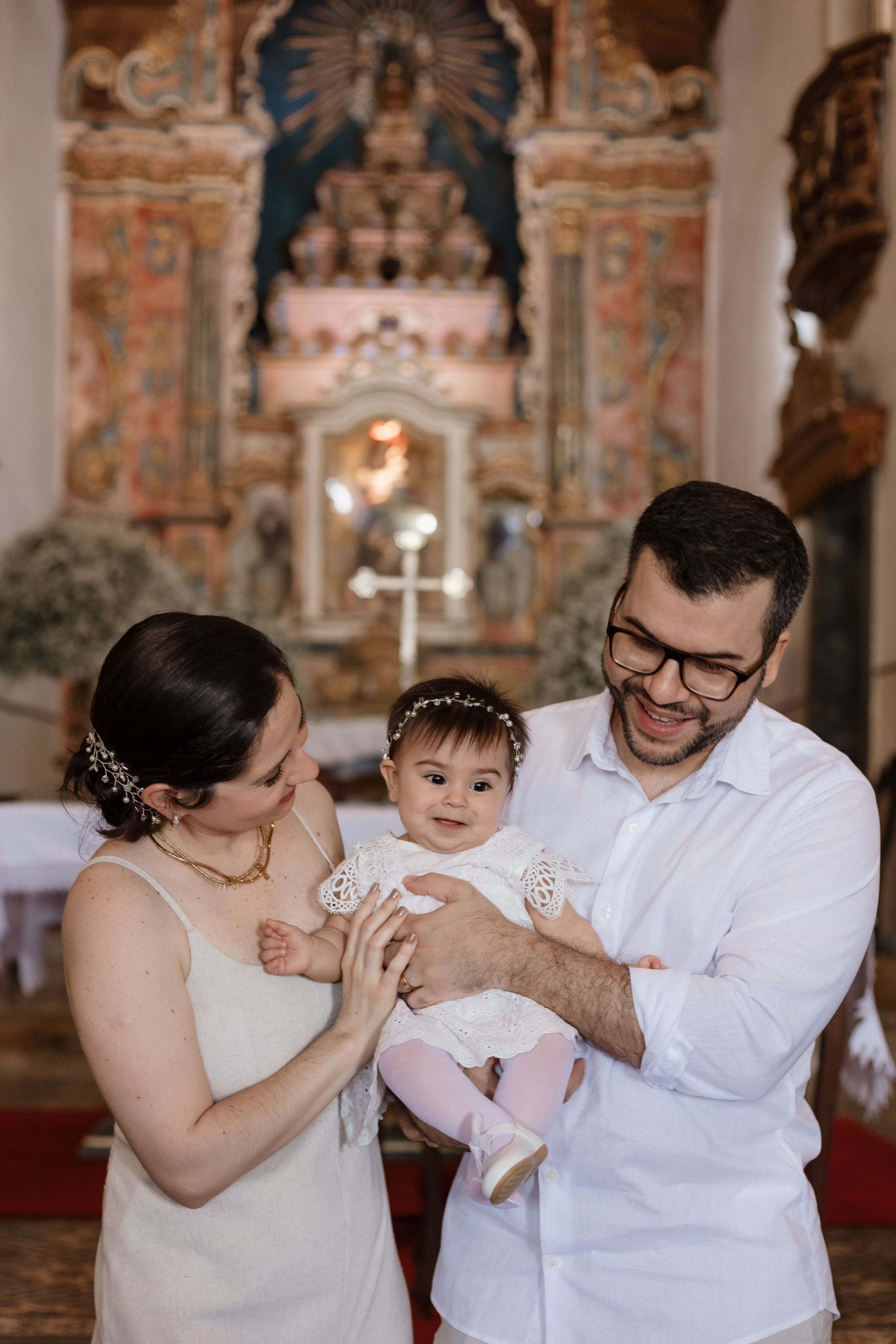 Pais com a bebê antes da cerimônia de batizado