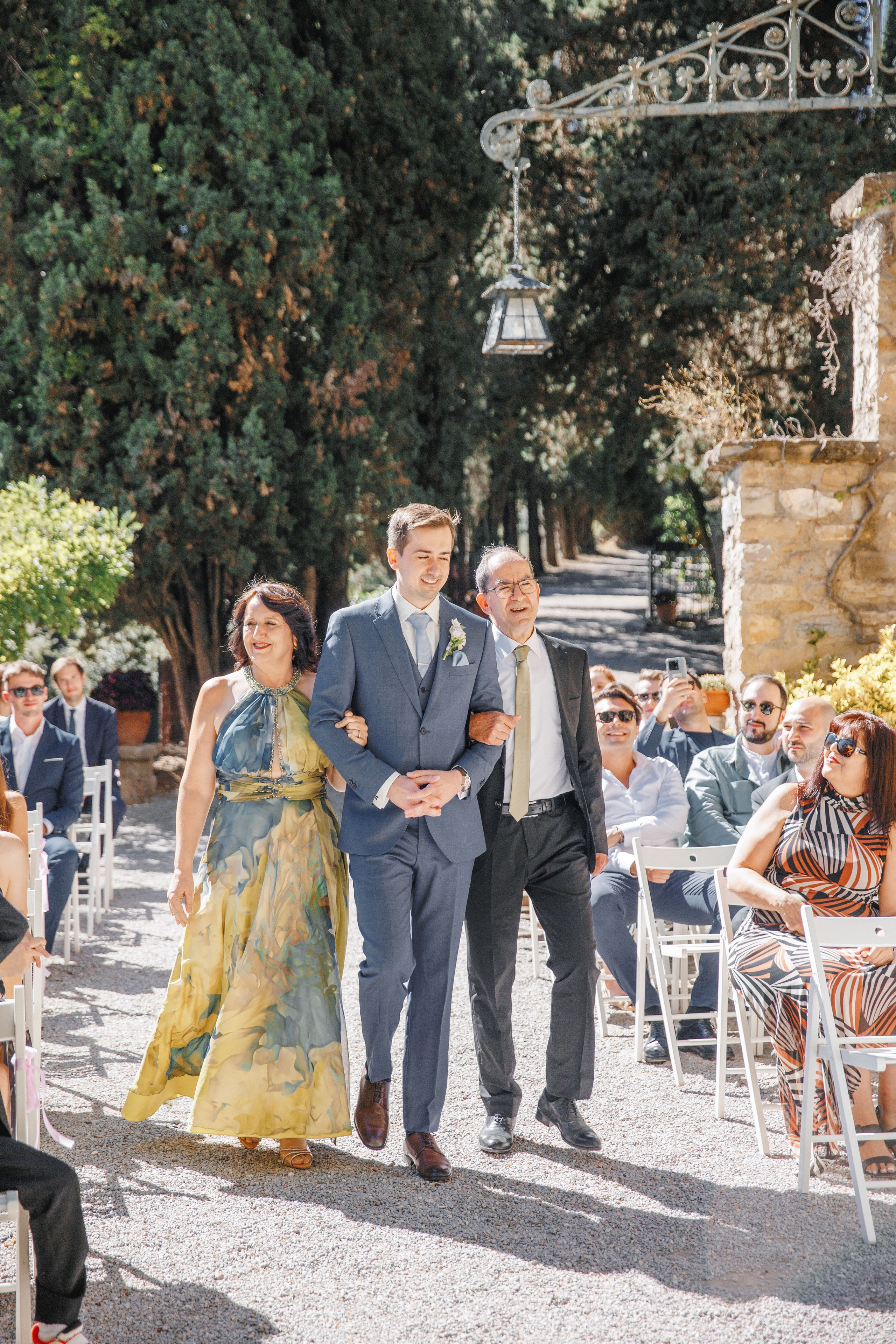 The groom is walking down the aisle with his parents in the historical wedding venue la Baronia.