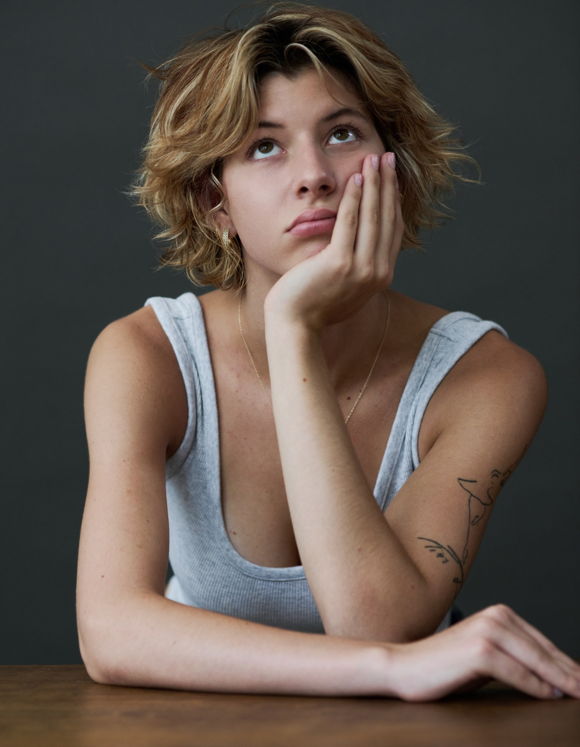 Female Photographer in Brussels. Portrait of a young woman sitting on a chair with her head tilted back, wearing a white tank top.