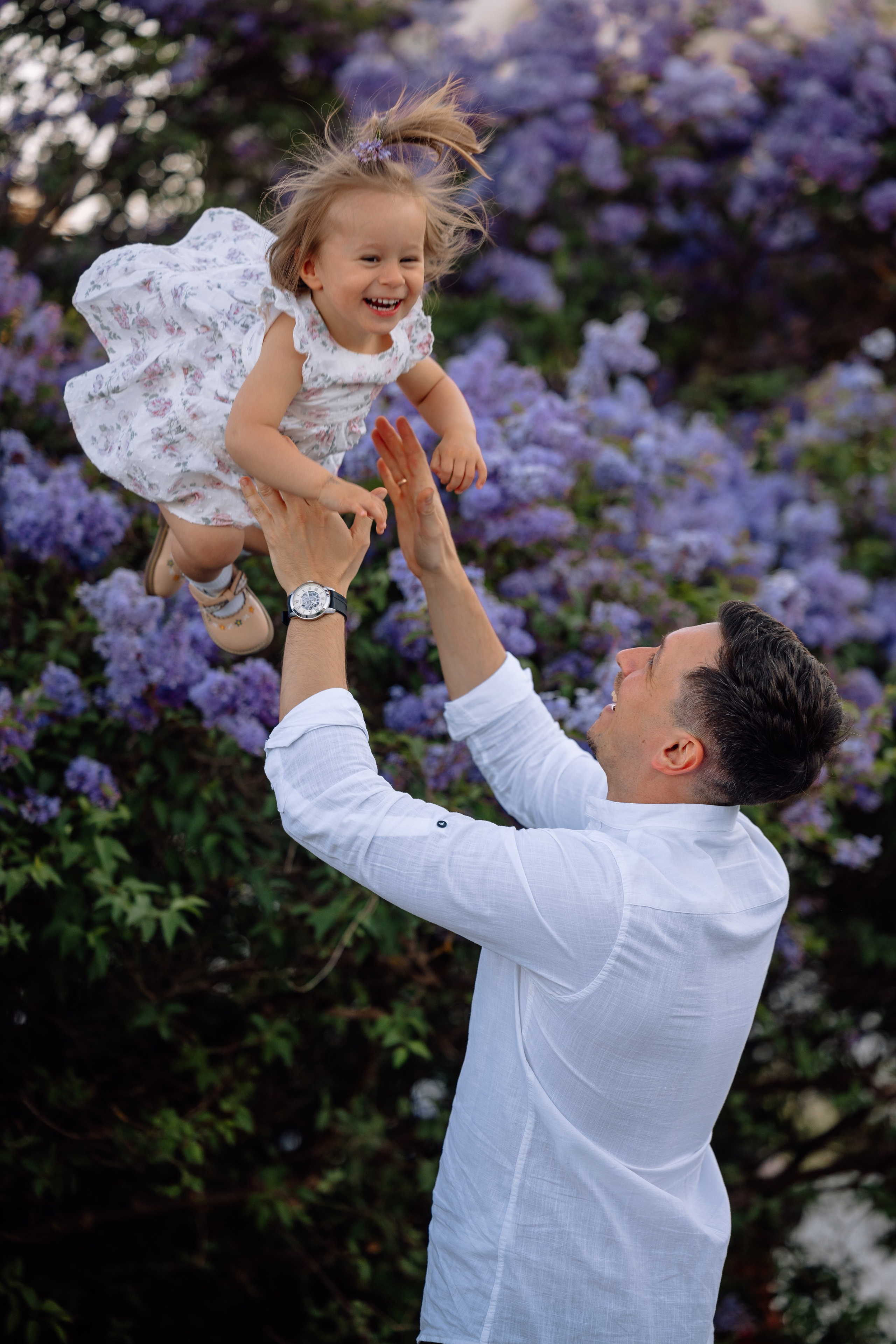 Papa wirft Tochter lachend in die Luft beim Familienfotoshooting am Schloss Nymphenburg