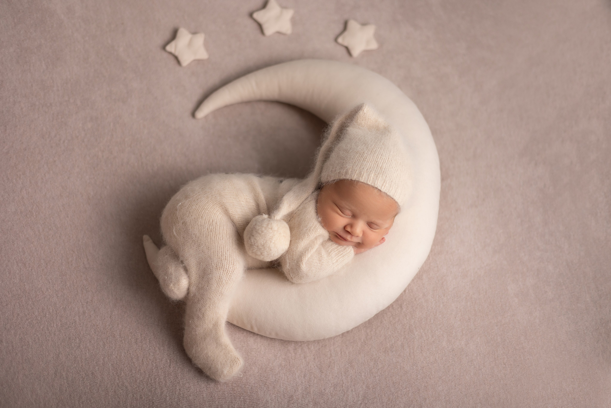 Neugeborenes Baby schläft friedlich auf einer Mondsichel – liebevolles Newbornshooting in Hagen.