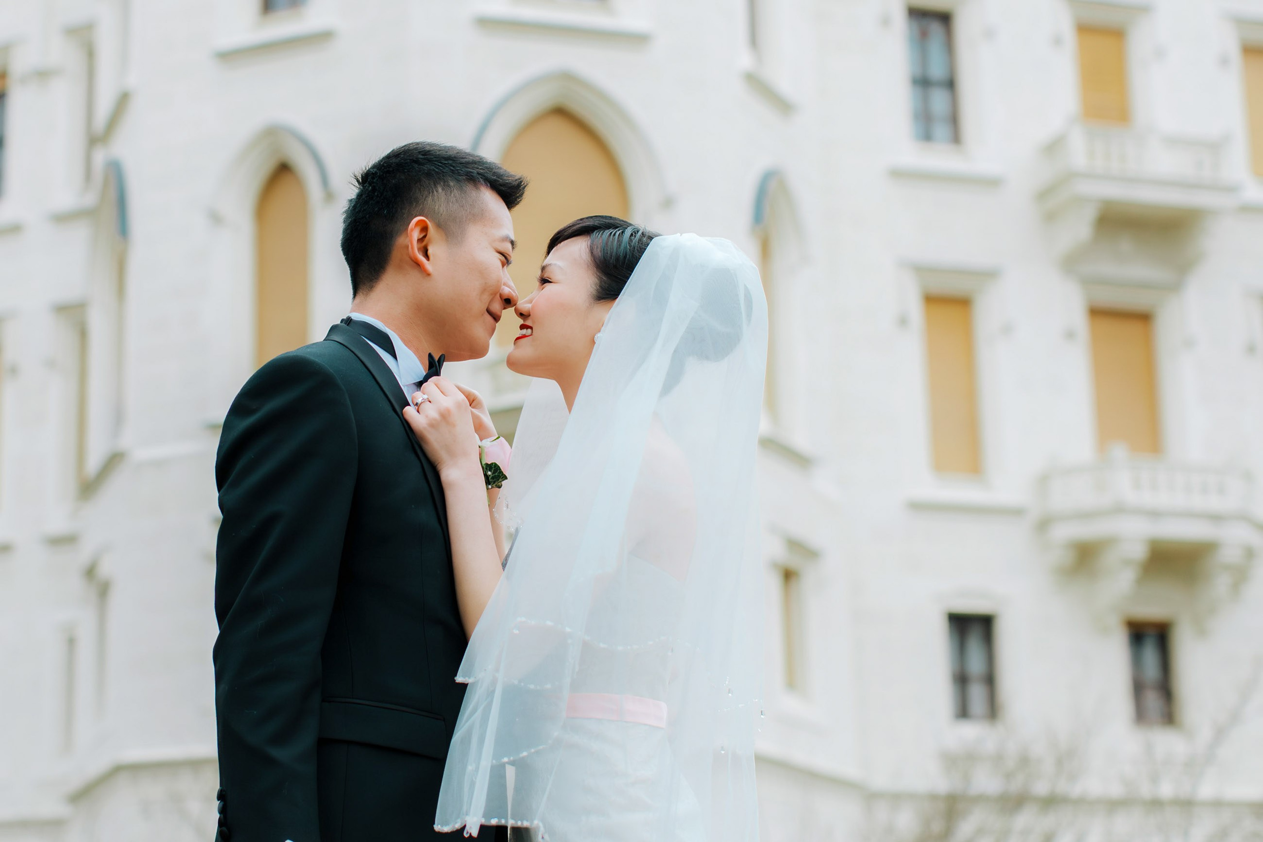 A smling Hong Kong bride & groom cuddle up as they explore the grounds of the State Chateau of Hluboka during their destination wedding.