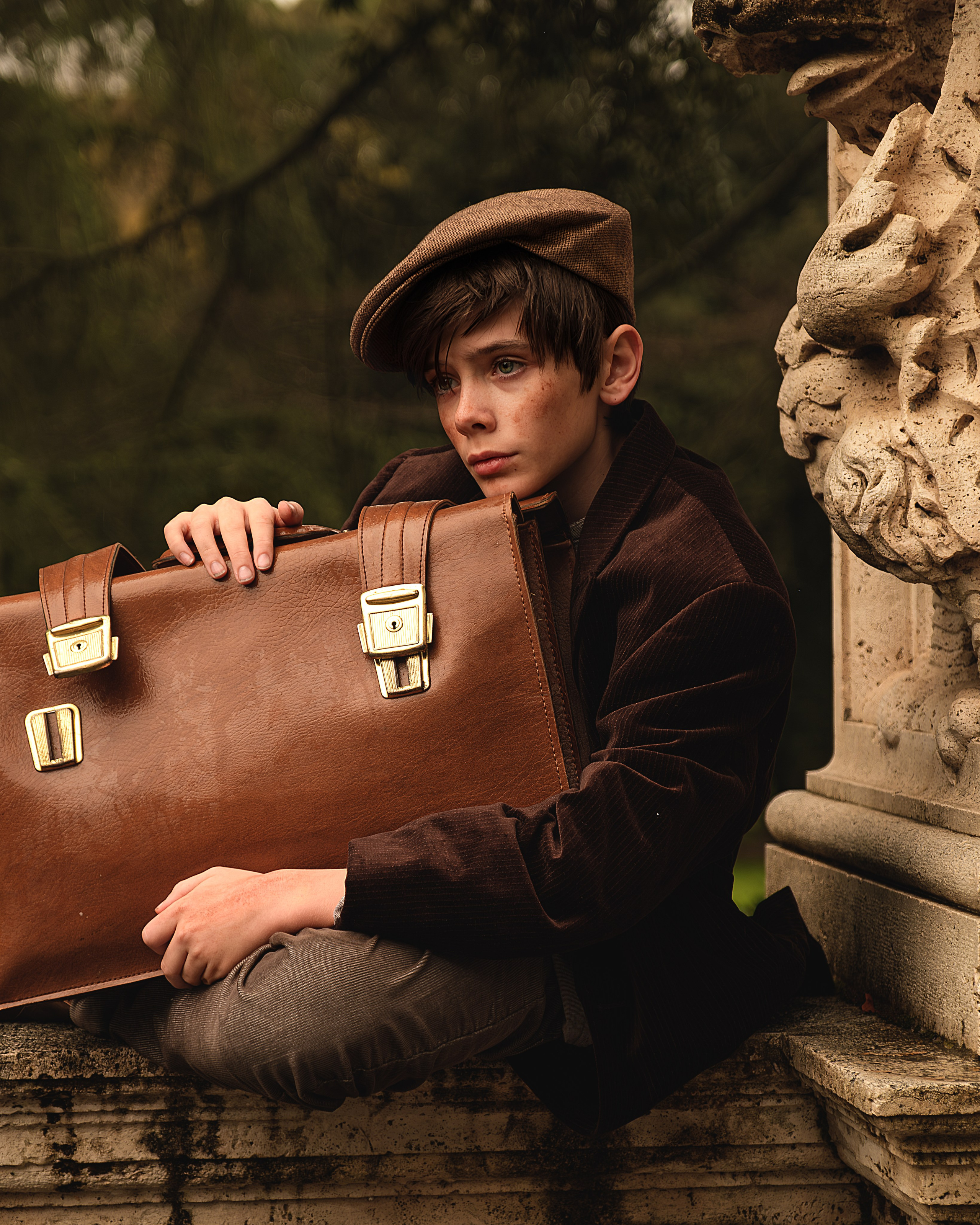 Ritratto fotografico artistico ragazzo povero seduto sul muretto