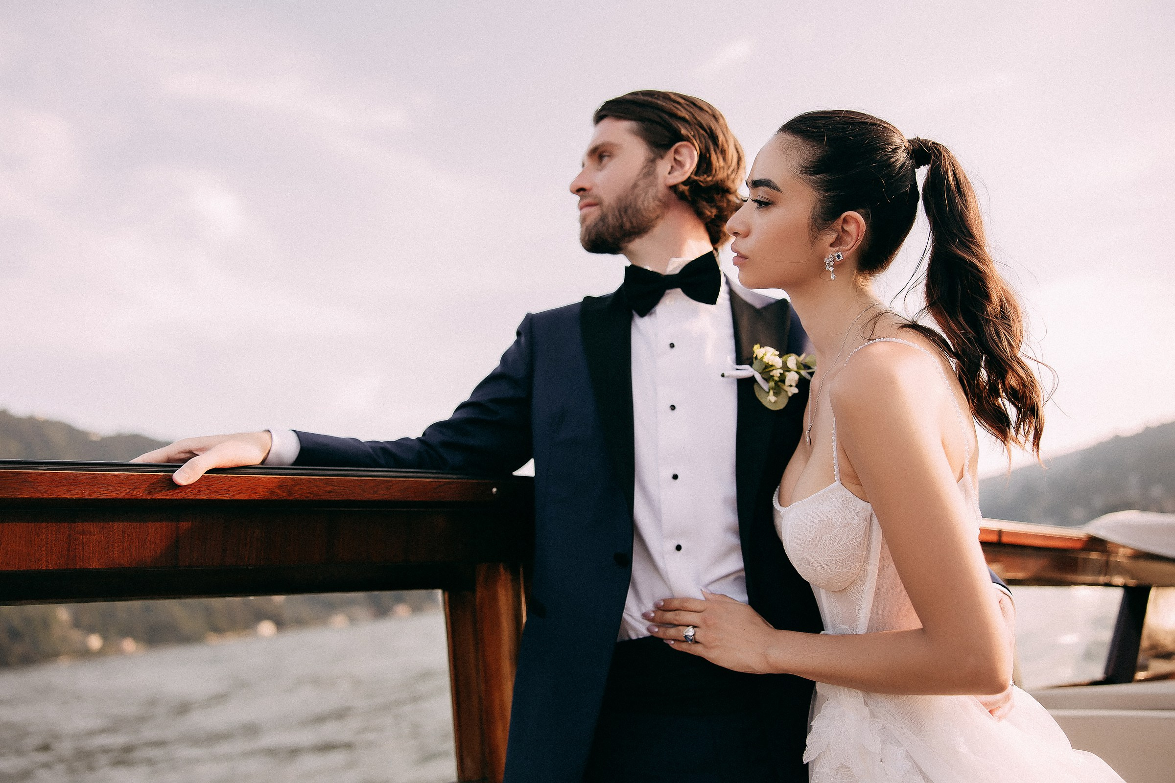 Bride and groom share a quiet moment, gazing into the distance on a boat.