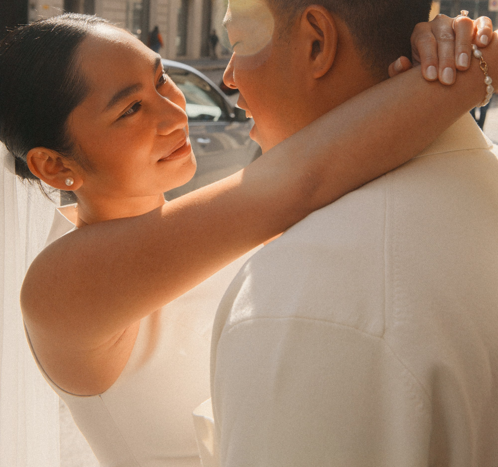 Romantic Engagement Portrait in Natural Light – Elegant Couple Photography. Close-up of an engaged couple embracing in soft natural light, with the bride showing her engagement ring and holding white flowers. A tender engagement portrait of a stylish couple wrapped in soft daylight, highlighting intimacy, love, and elegance. A timeless pre-wedding photography moment filled with emotion and natural beauty. engagement photography, romantic couple portrait, pre wedding photoshootnatural light photography, love story photography, intimate couple moment,engagement ring detailwedding photography inspiration, modern engagement session, elegant couple portrait