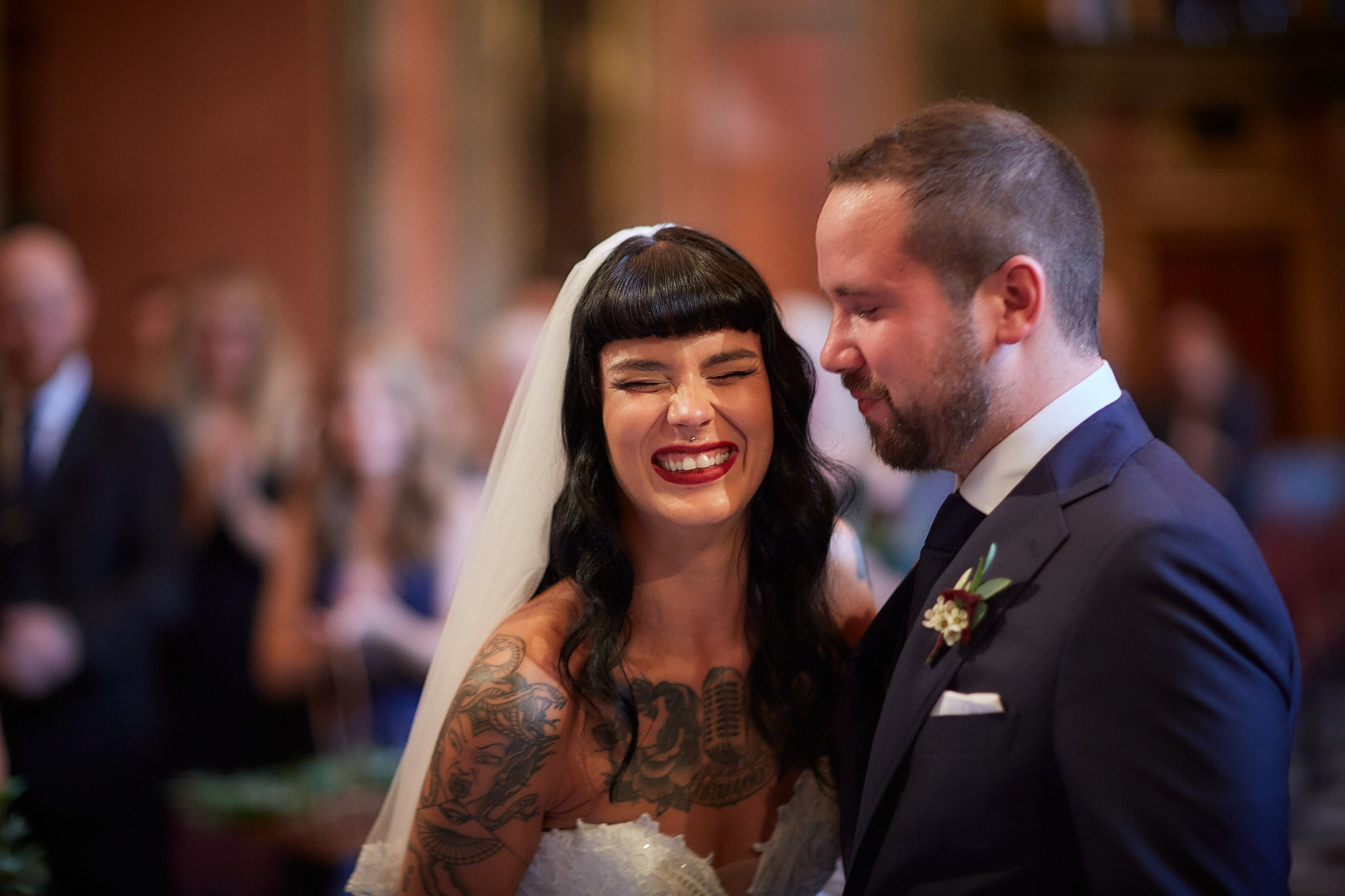 Bride beaming at teary-eyed groom during intimate ceremony moment.
