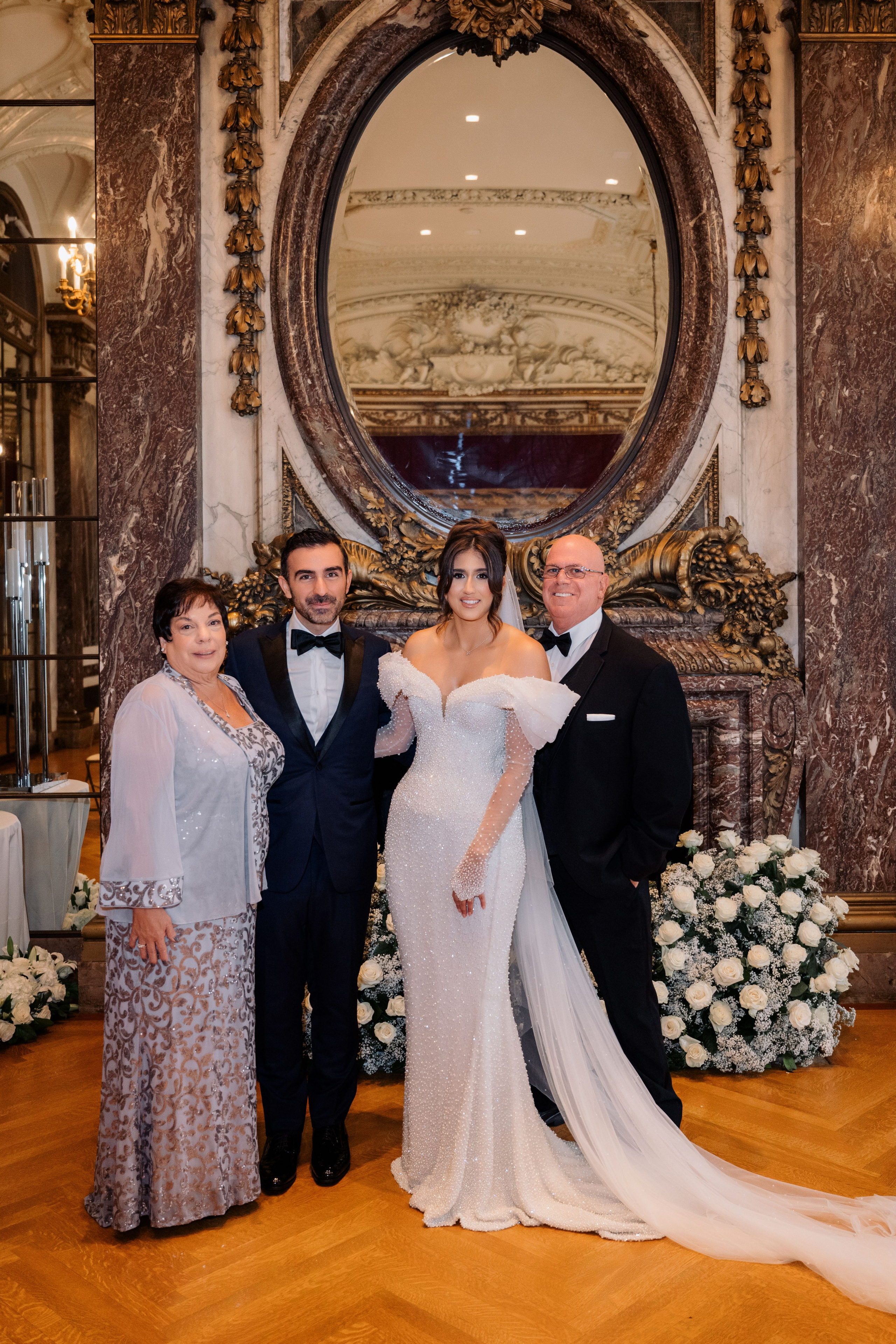 a bride and groom pose for a photo with their family