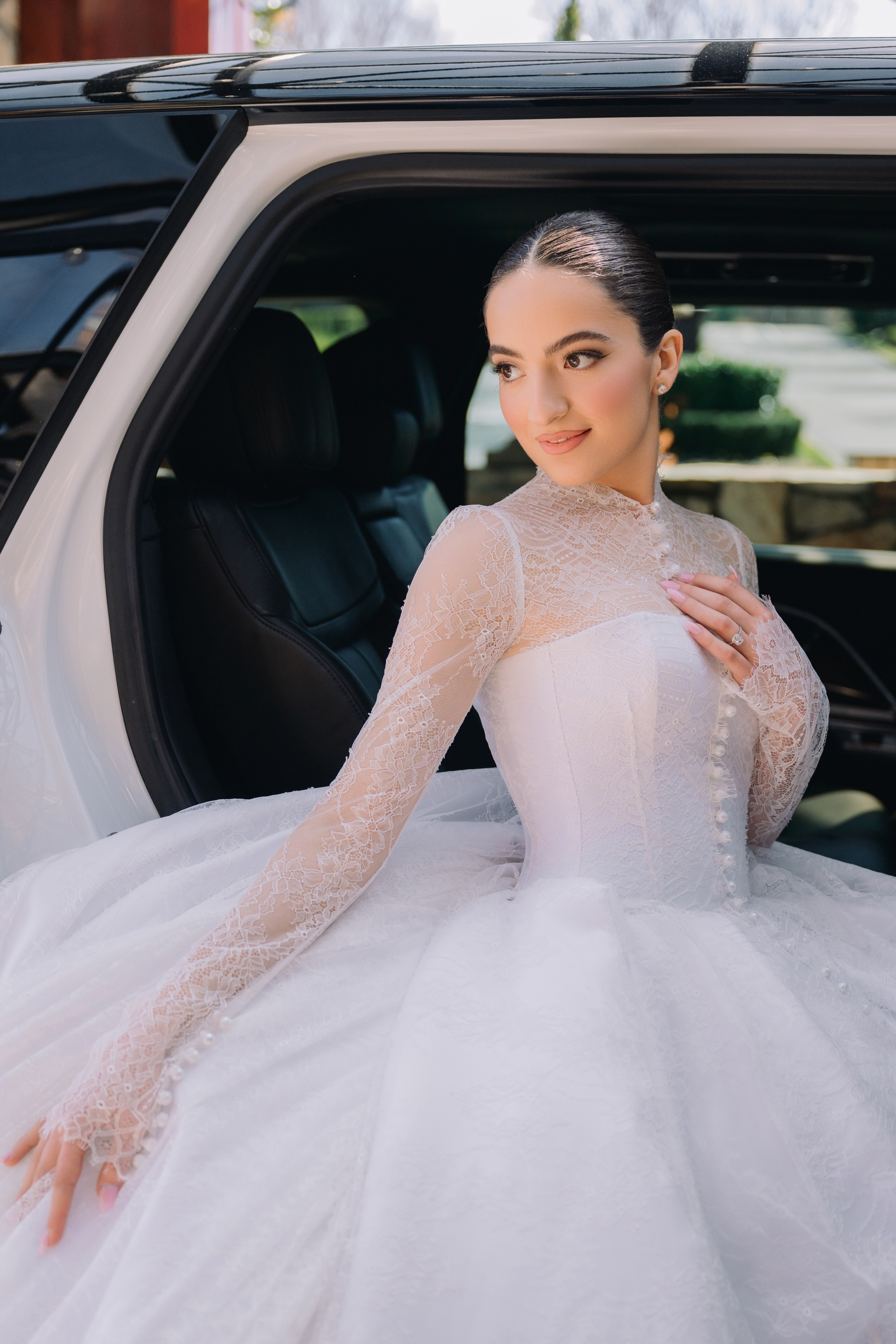a woman in a white wedding dress sitting in the back of a car