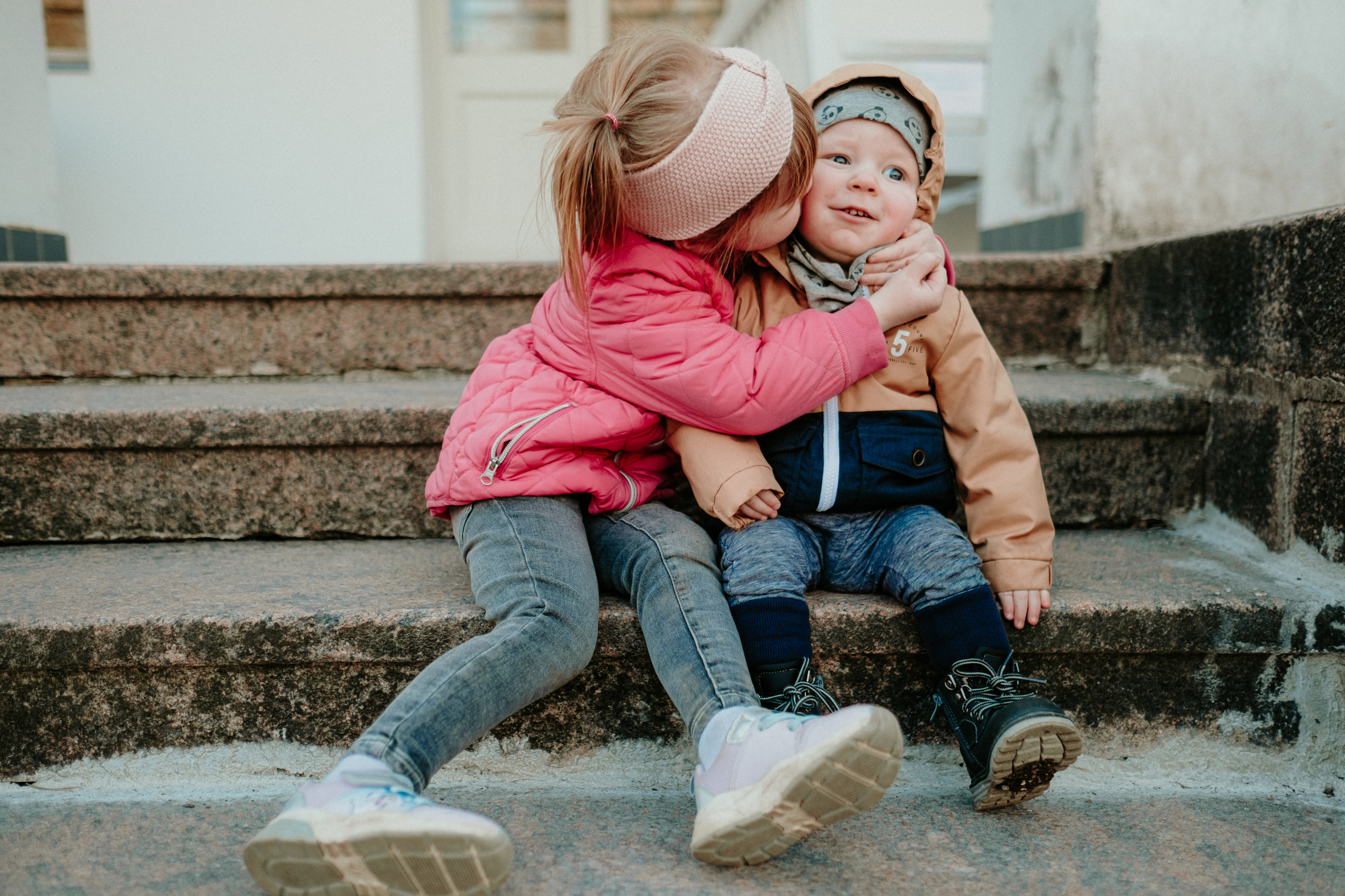 Māsiņa dod brālītim buču uz vaiga. Foto pie Lūznavas muižas kāpnē,.