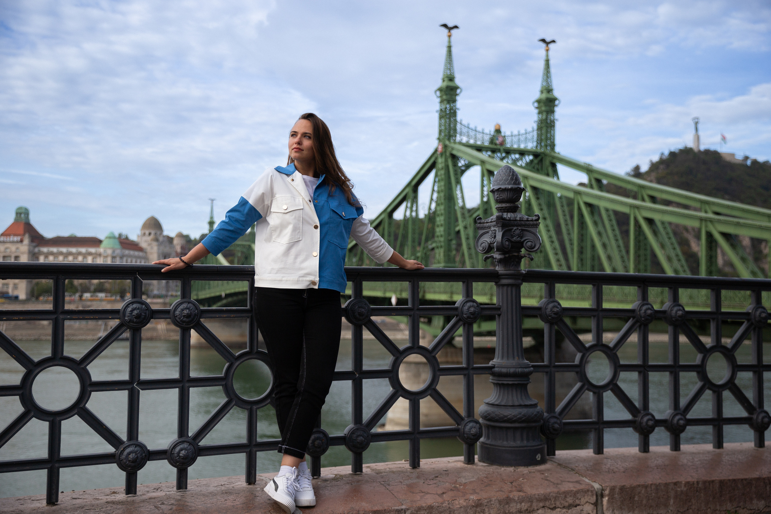 A photo of a girl in a white and blue jacket, taken from the Freedom Bridge in Budapest