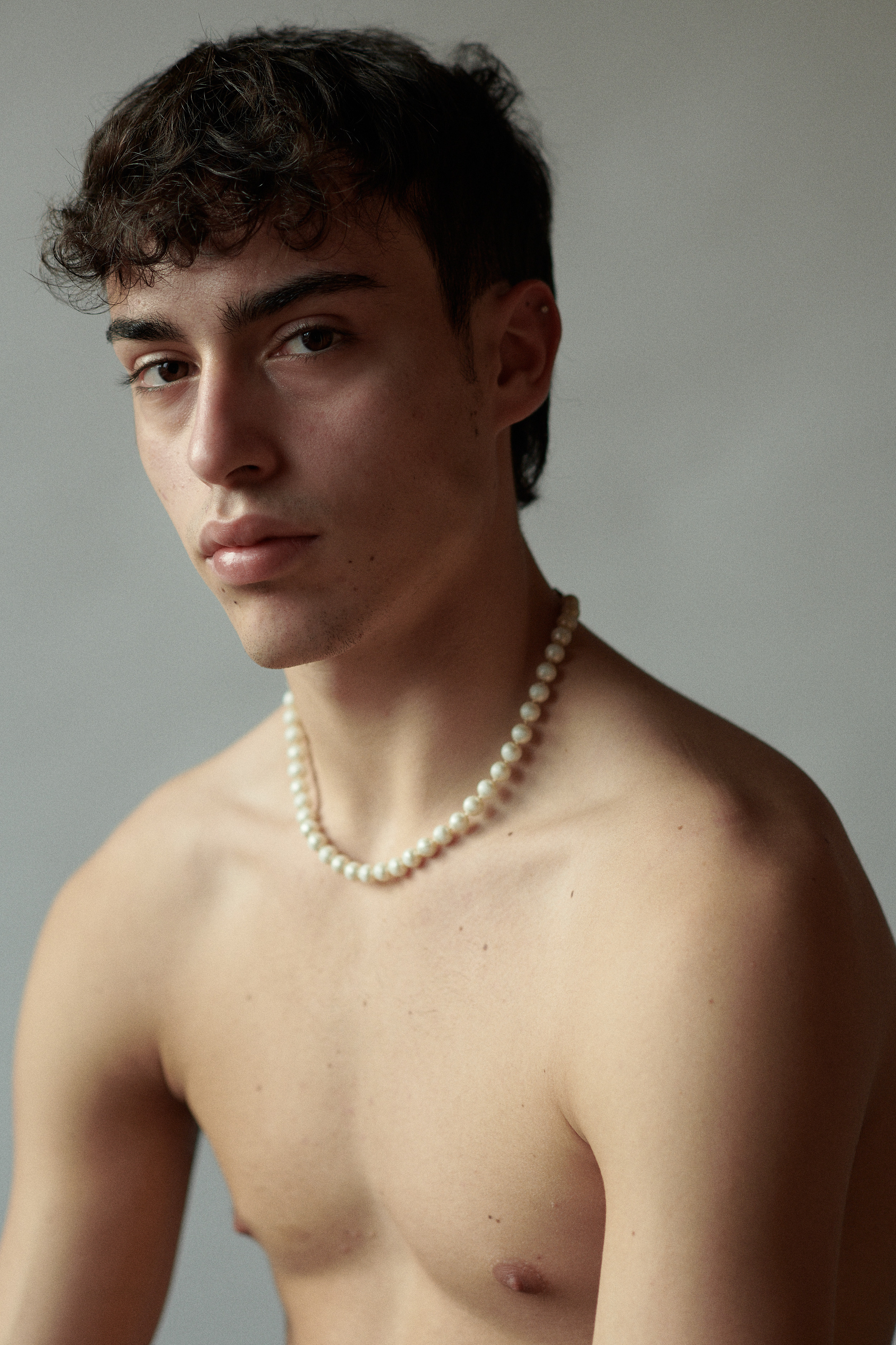 Portretfoto van een jonge man met een parelketting, fotograaf Victoria Ushkanova gevestigd in Nederland en Los Angeles.