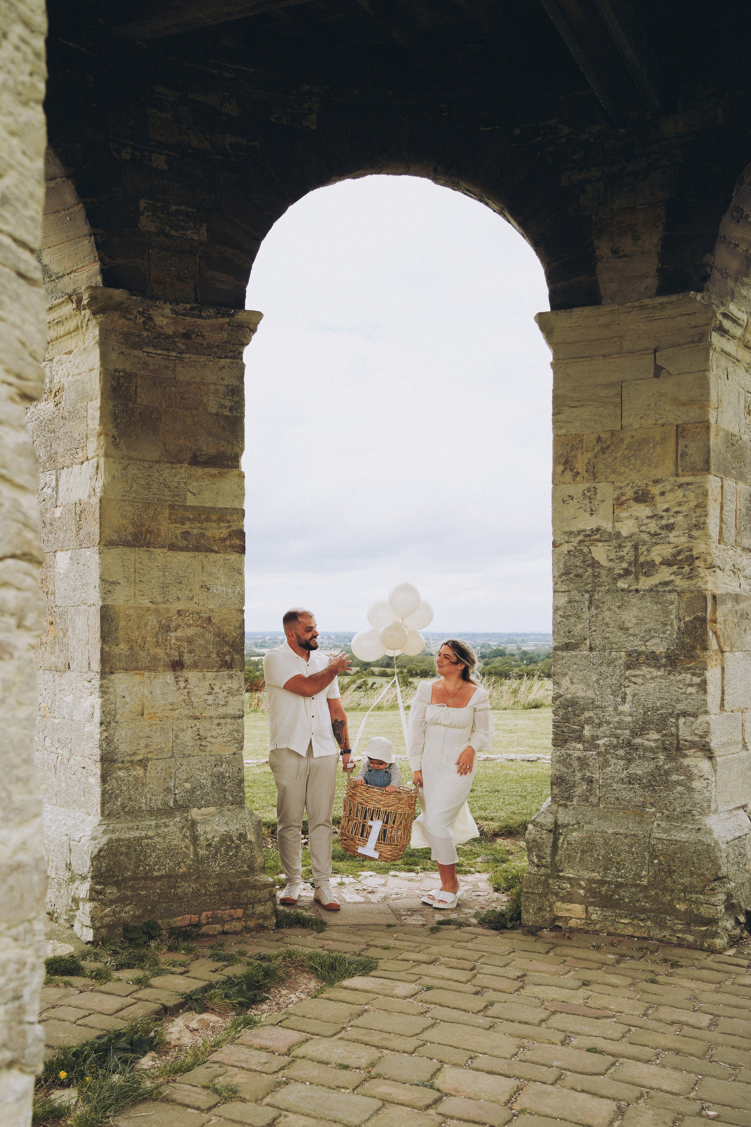 Family walking together through a stone archway during a relaxed outdoor family photoshoot