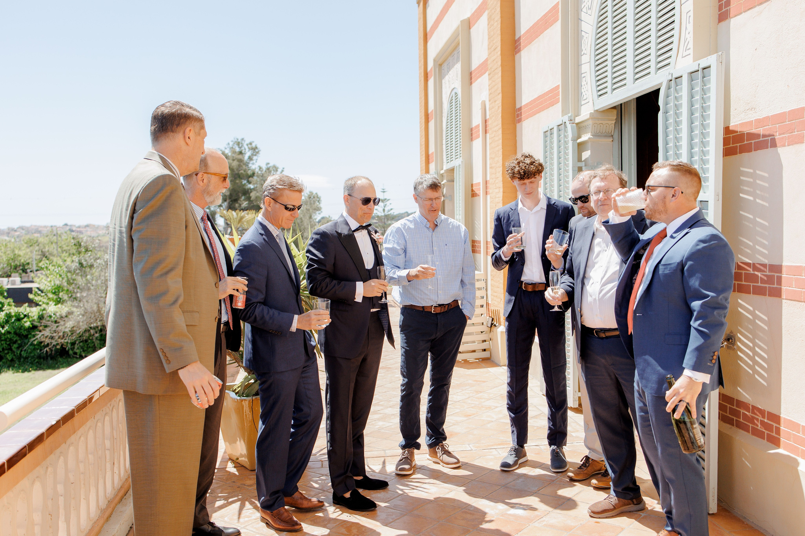 Groom and his friends having a dring on the terrase of the stunning wedding venue in Spain