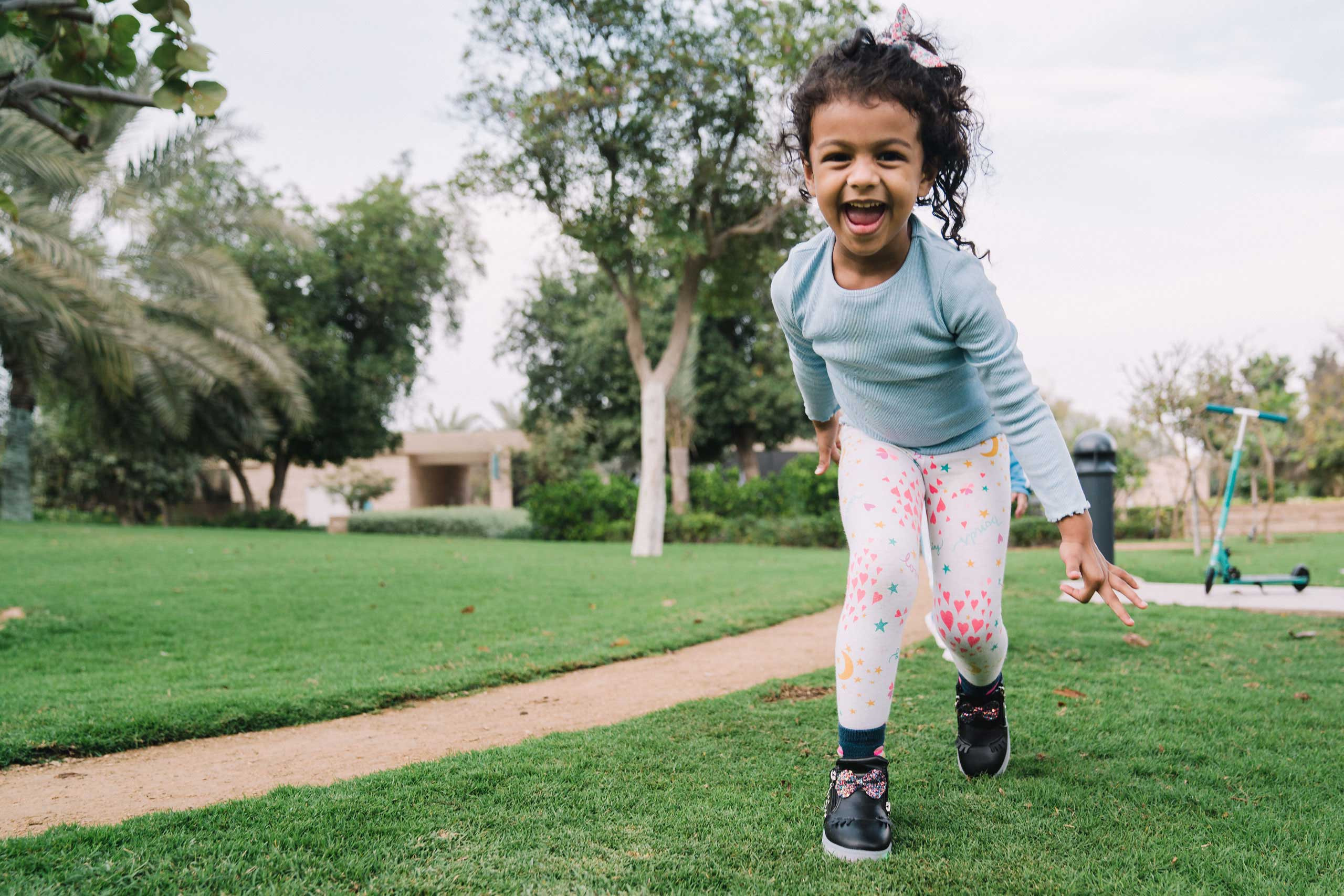african girl running and happily smiling among the trees in the Um El Emarat park