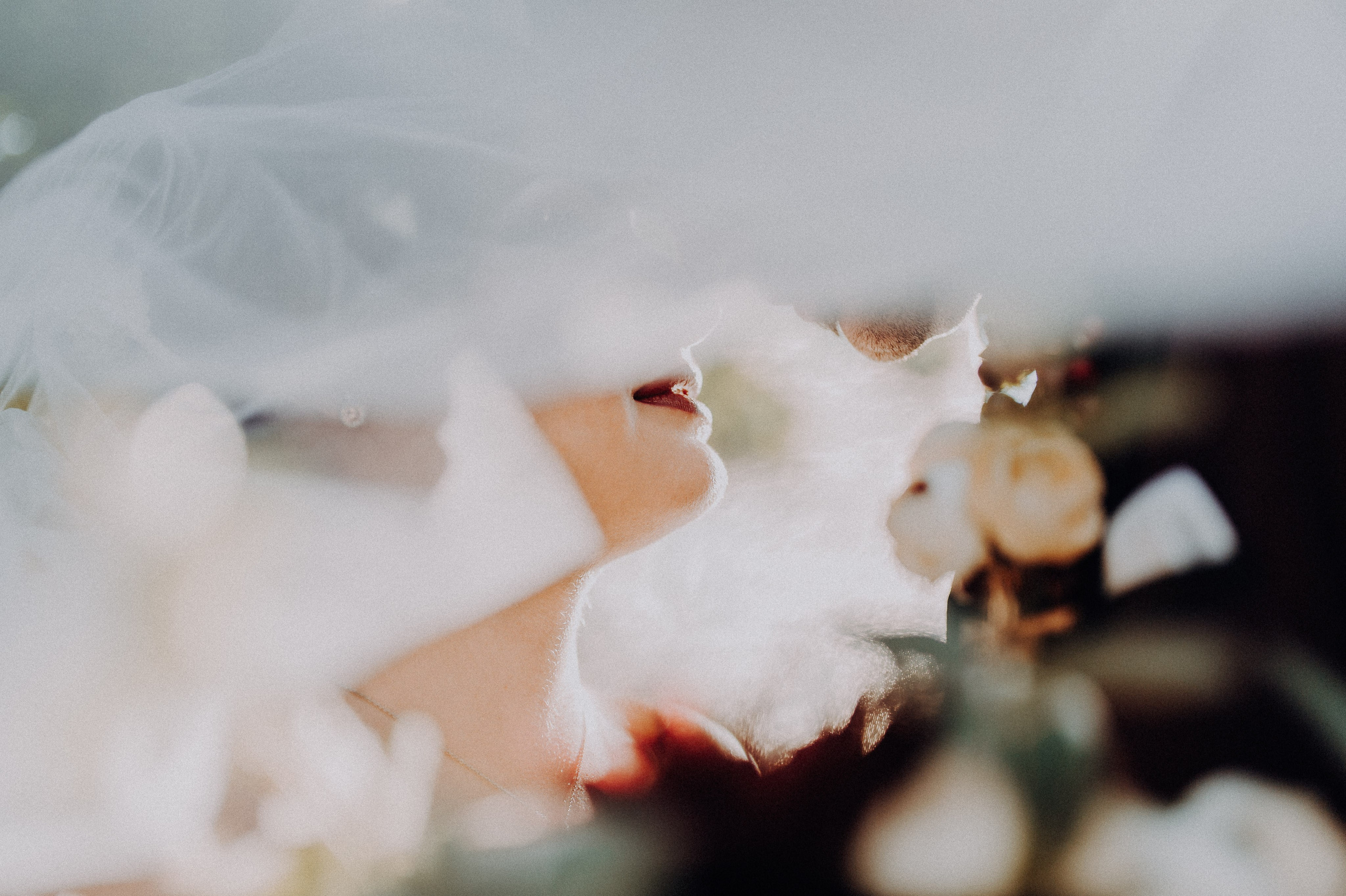 Mireasa și mirele zâmbind fericiți, acoperiți de voalul miresei, într-un moment intim și romantic.