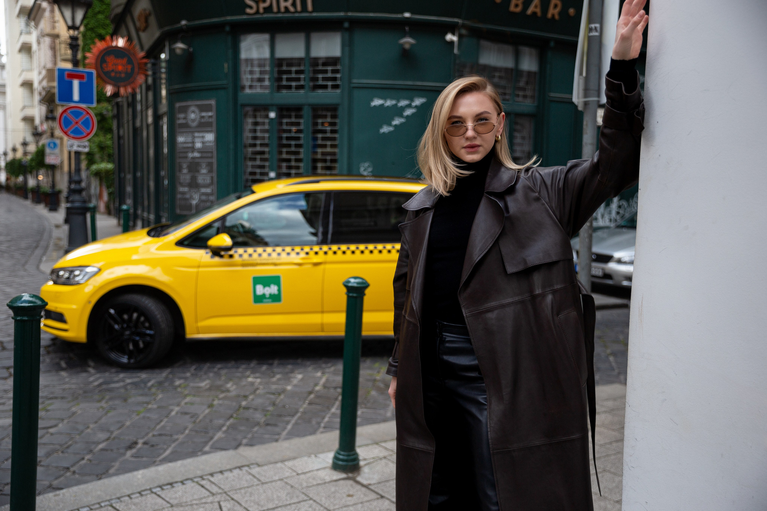 a photo of a girl on the streets of Budapest, with a yellow taxi in the background