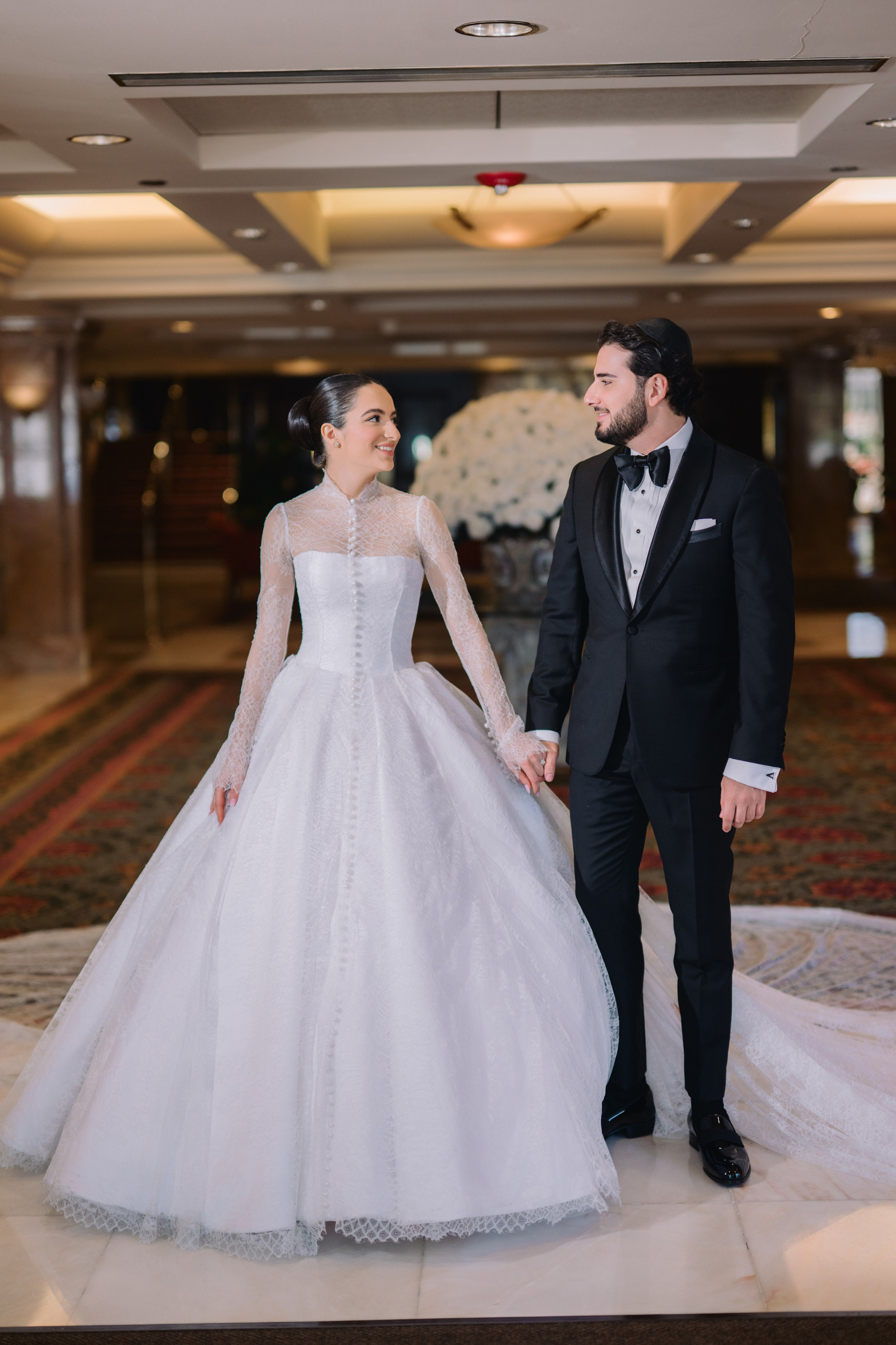 a bride and groom holding hands in a hotel lobby