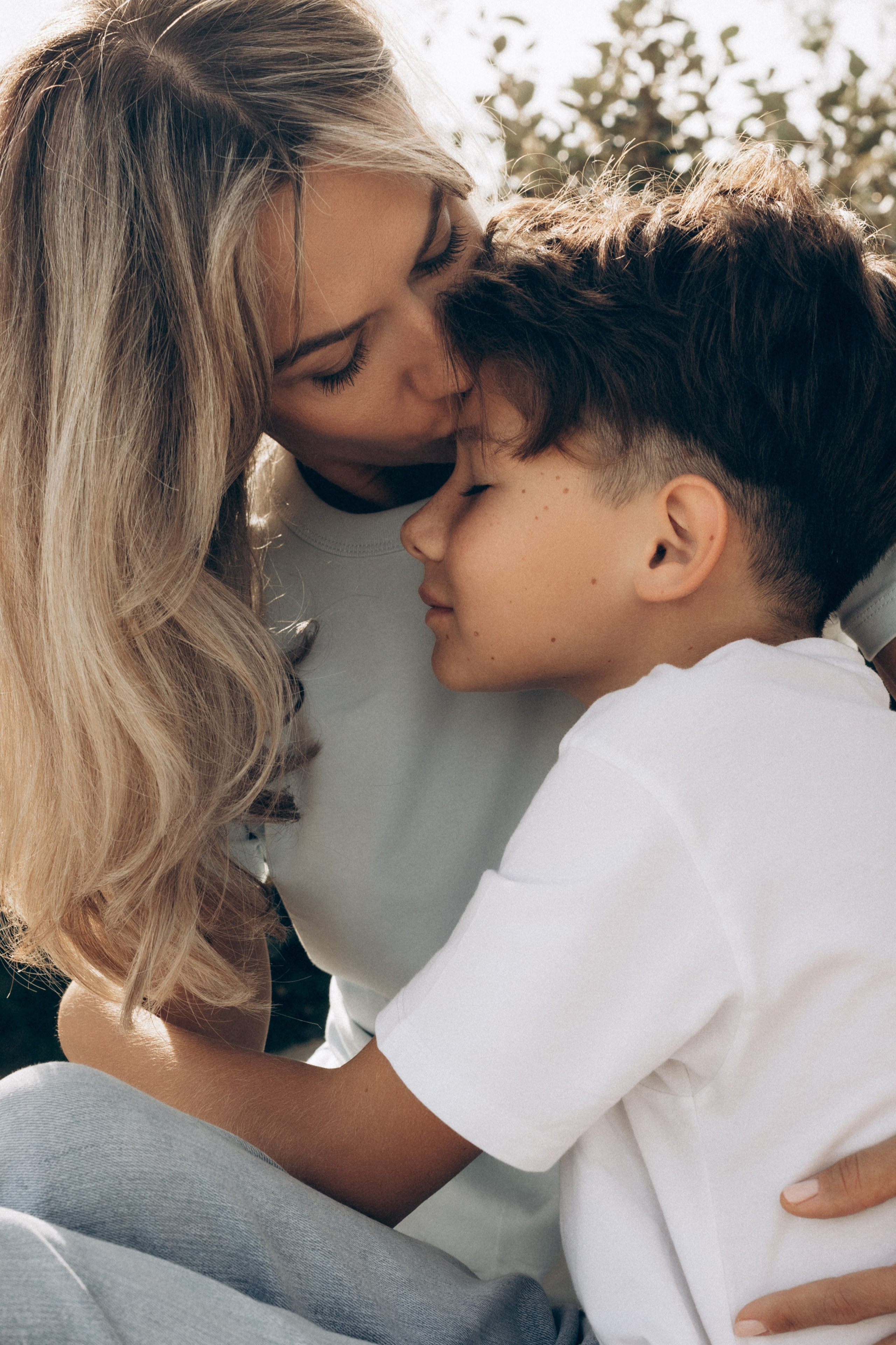 Una madre bacia dolcemente il figlio durante un servizio fotografico di famiglia sul mare a Rimini. Luce naturale, atmosfera intima e legame autentico tra genitore e bambino sulla costa adriatica.