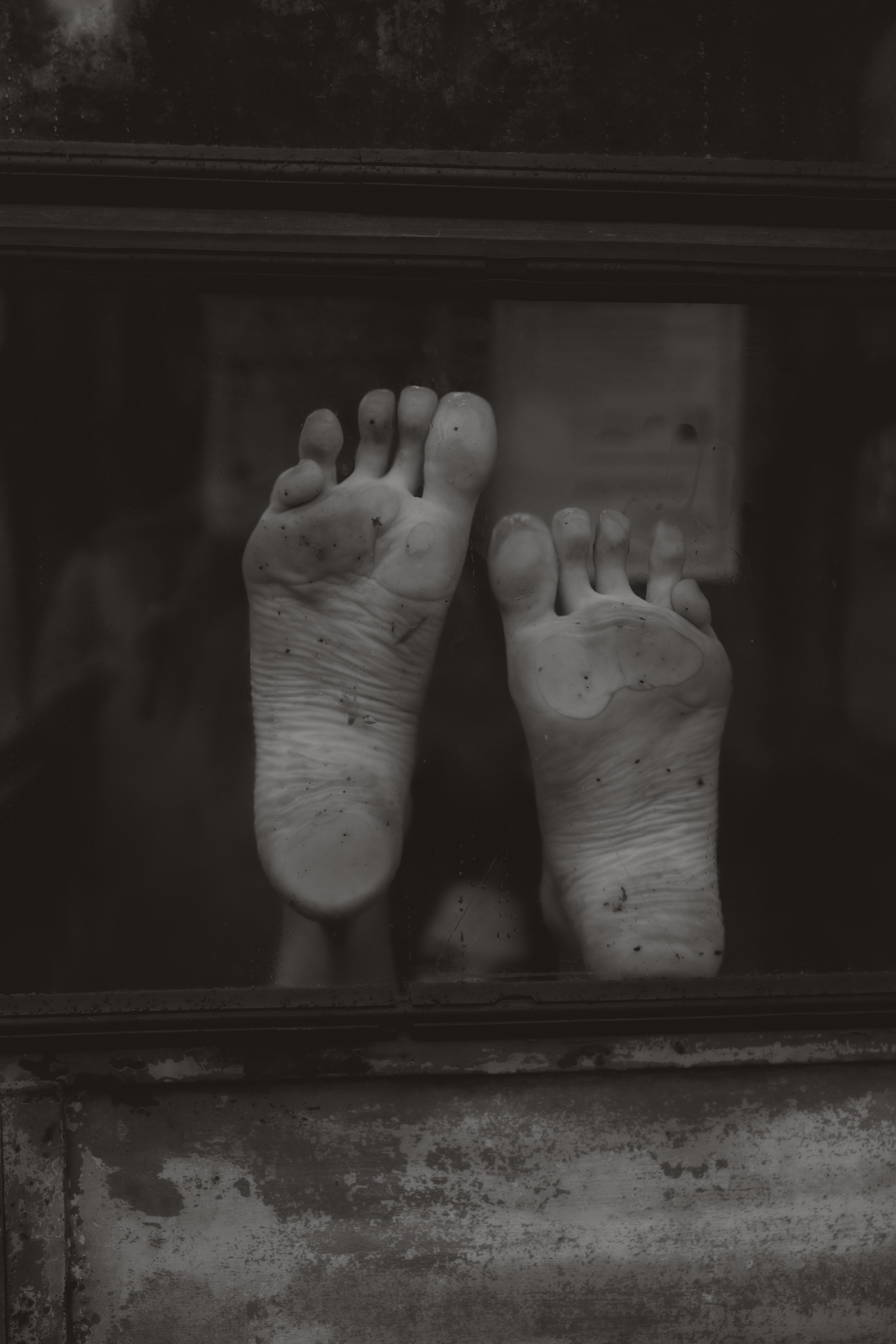 Fine art detail of bare feet seen through a window, conceptual portrait