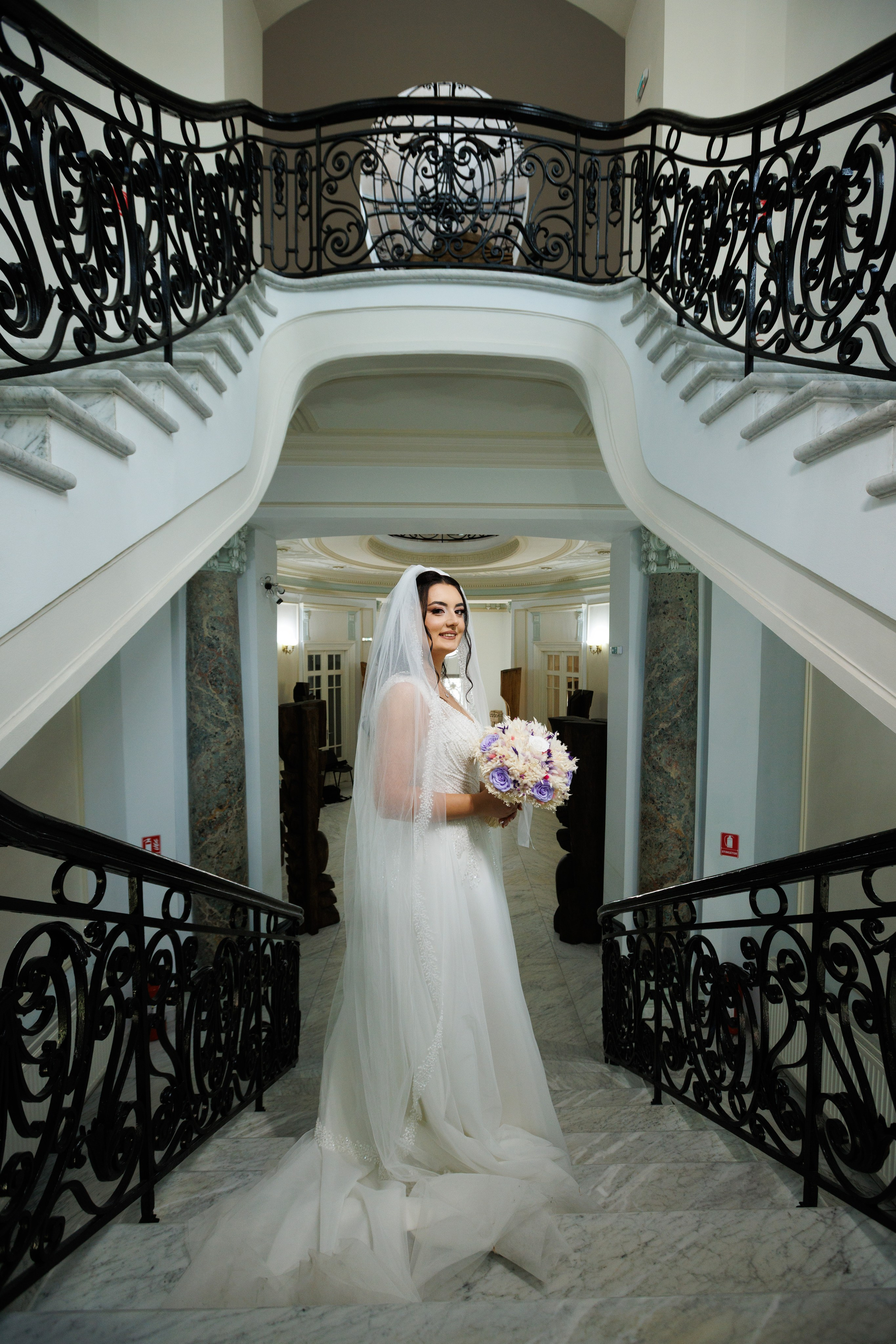 Gabriela, mireasă cu buchet colorat, fotografiată pe scara interioară