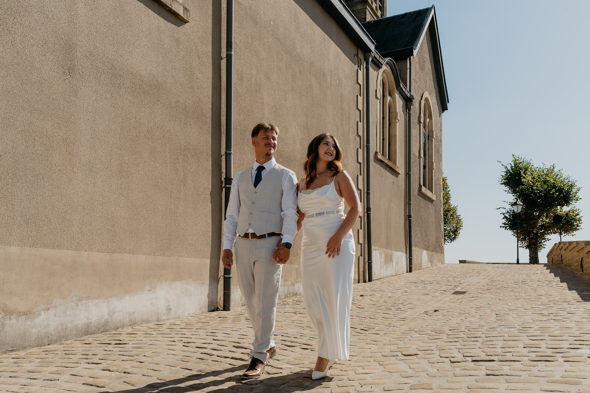 Mire și mireasă mergând pe o alee pietruită din Arlon, Belgia