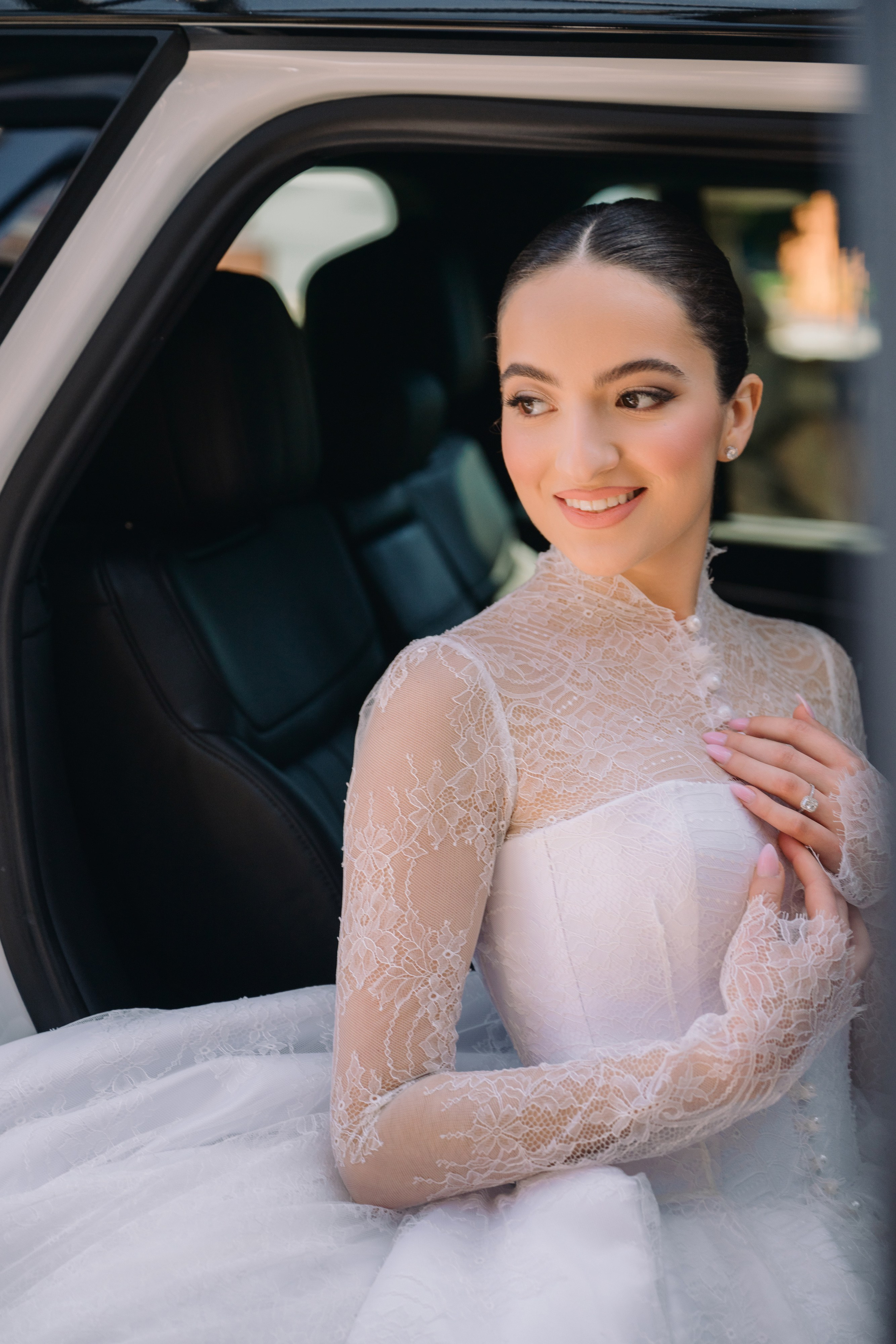 a woman in a white dress is sitting in the back of a car