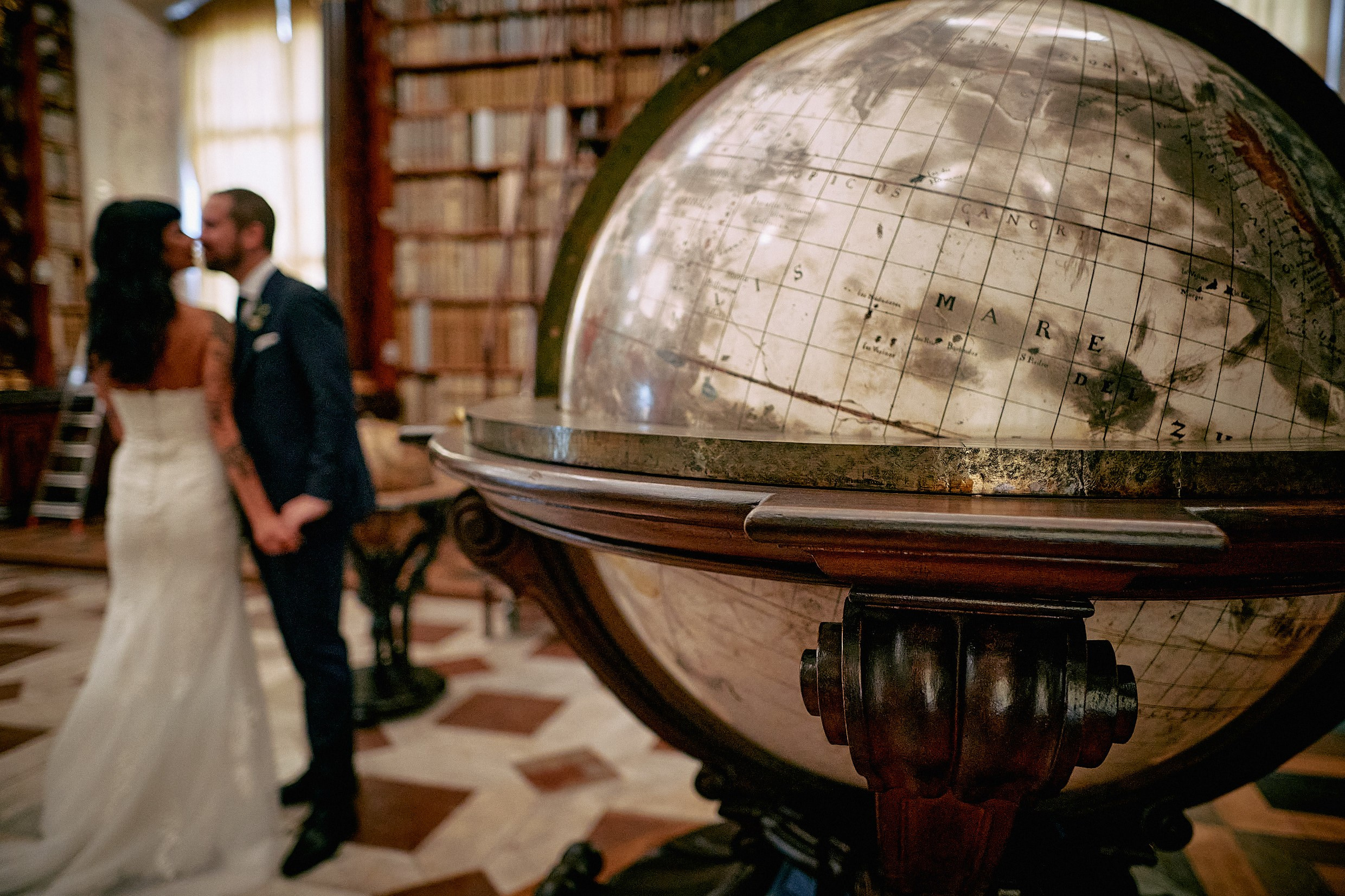 Terrestrial globe framing newlyweds kiss in Klementinum Astronomical Library.