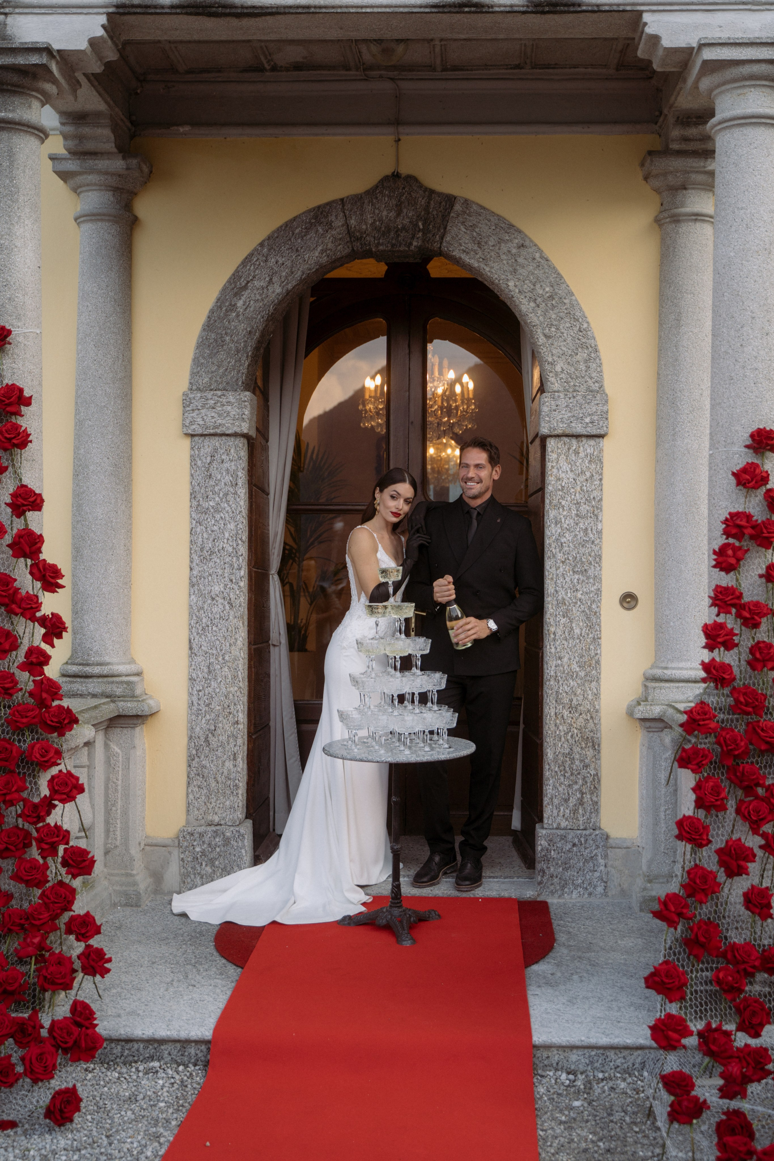 The newlyweds are preparing to pour champagne into the tower of glasses