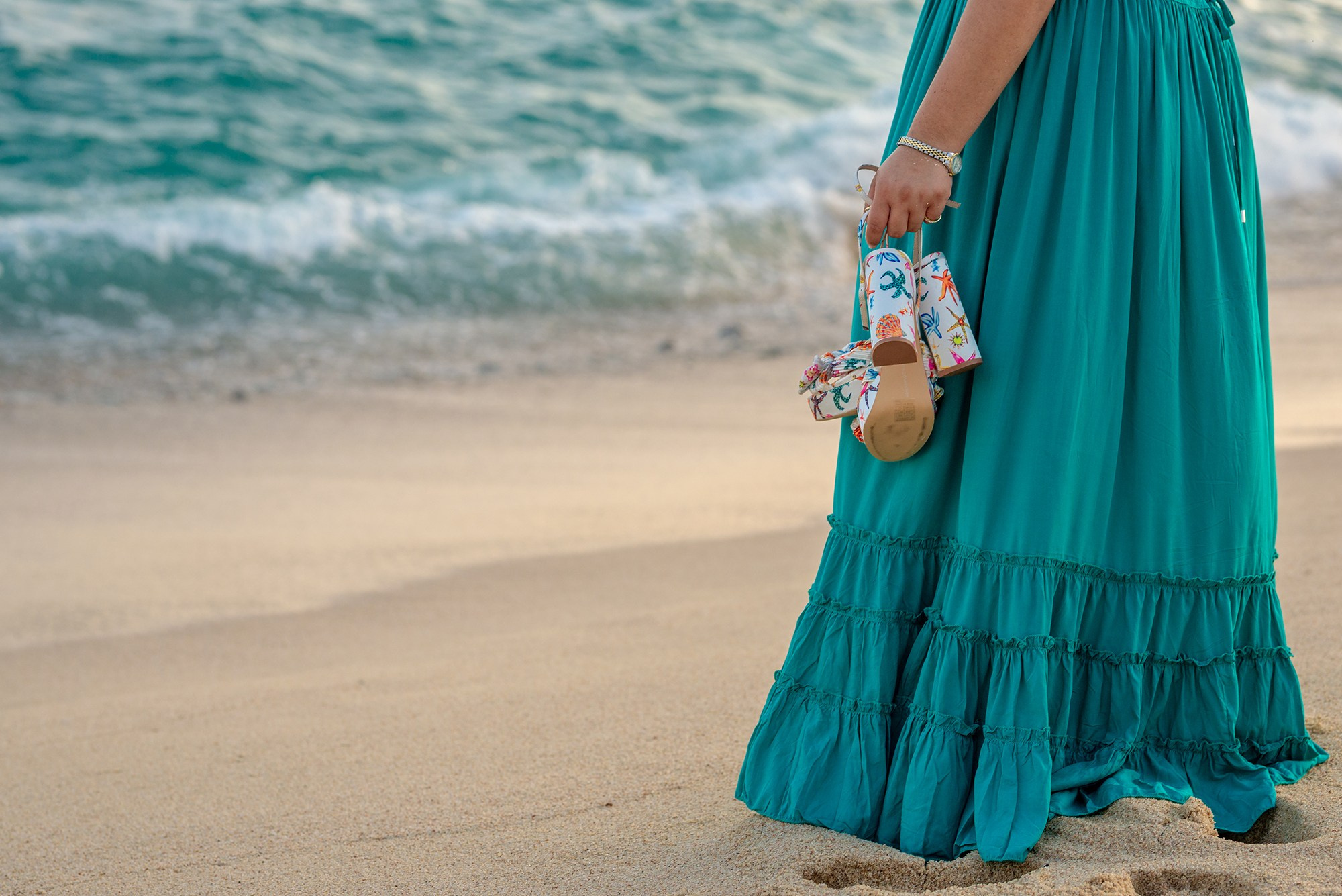 Woman walking along shoreline in turquoise dress at golden hour during lifestyle session in Los Cabos