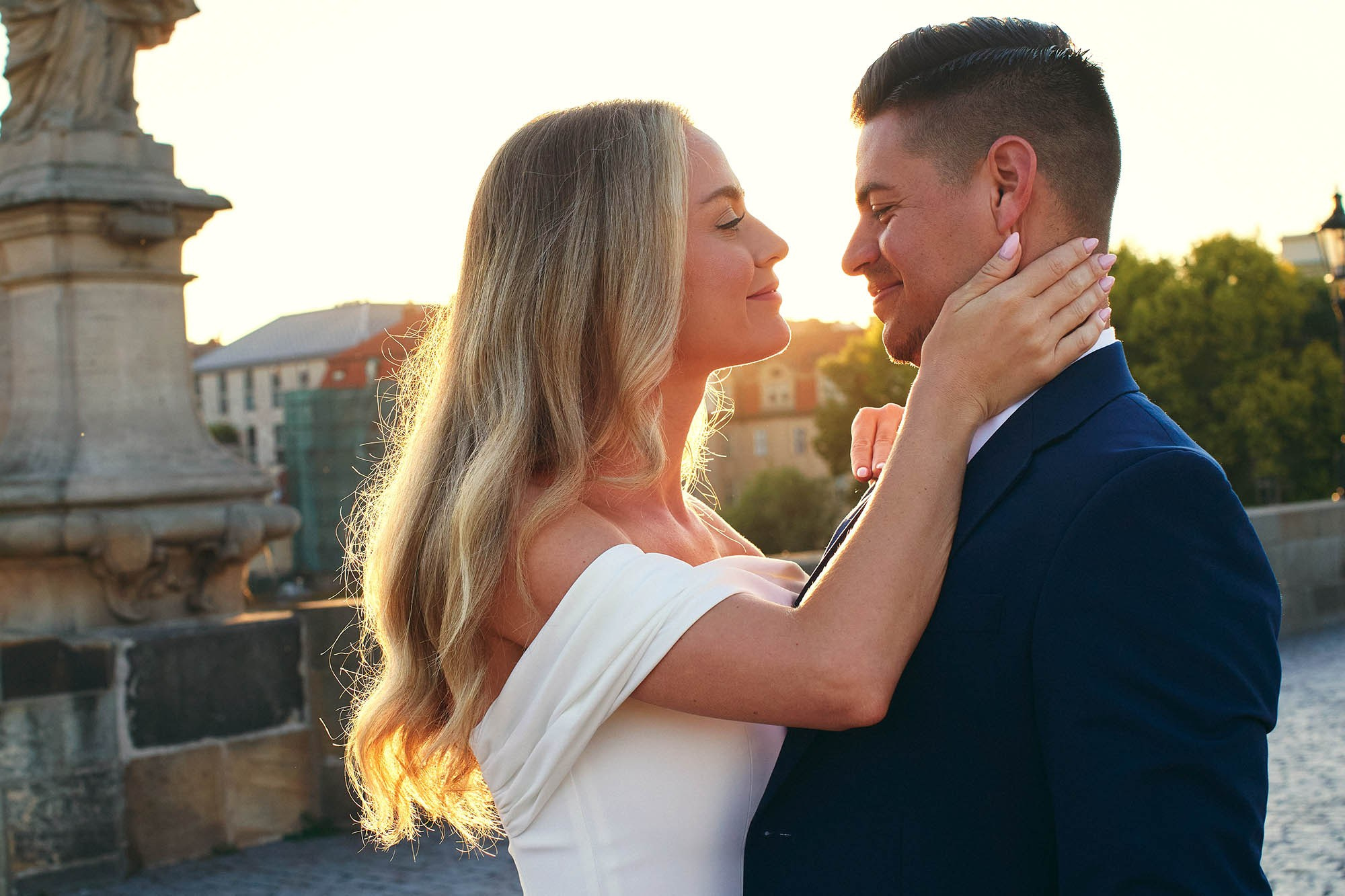 Engaged California couple surrounded by dramatic sunflare on empty Charles Bridge.