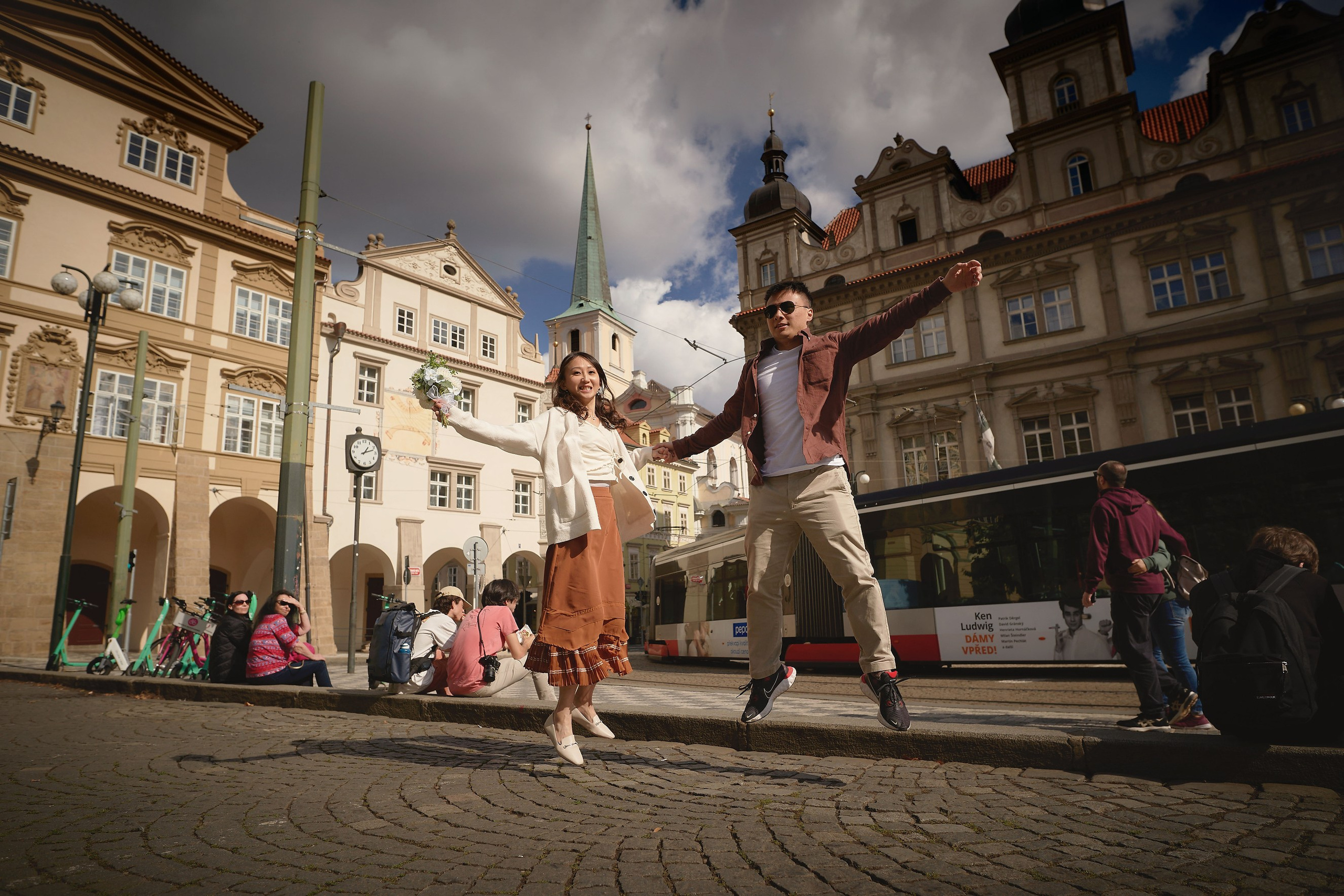 Eva and Conan jumping for joy with the tram in frame in Malostranské náměstí, Prague.