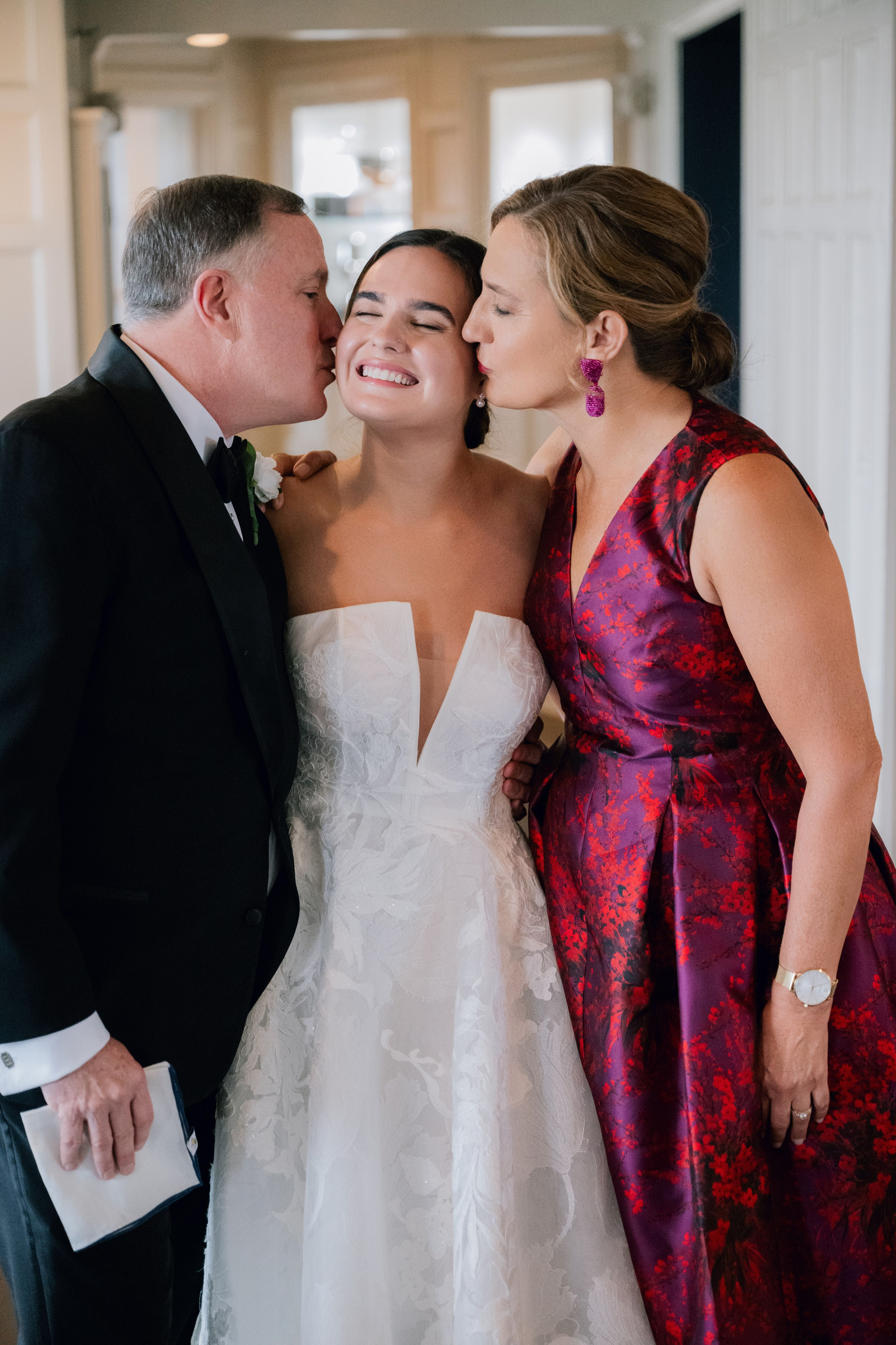 a bride and her father kiss on the cheek of their bride