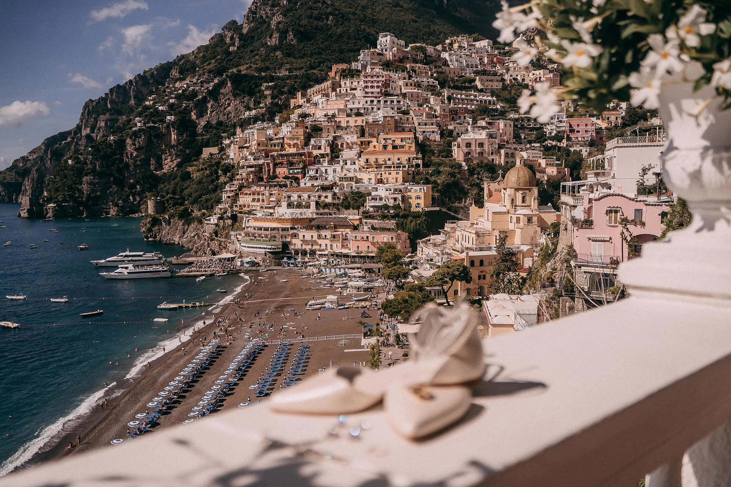 A picturesque view of the vibrant cliffside town of Positano as seen from a balcony at Villa Bohème, with bridal shoes and jewelry subtly displayed in the foreground.