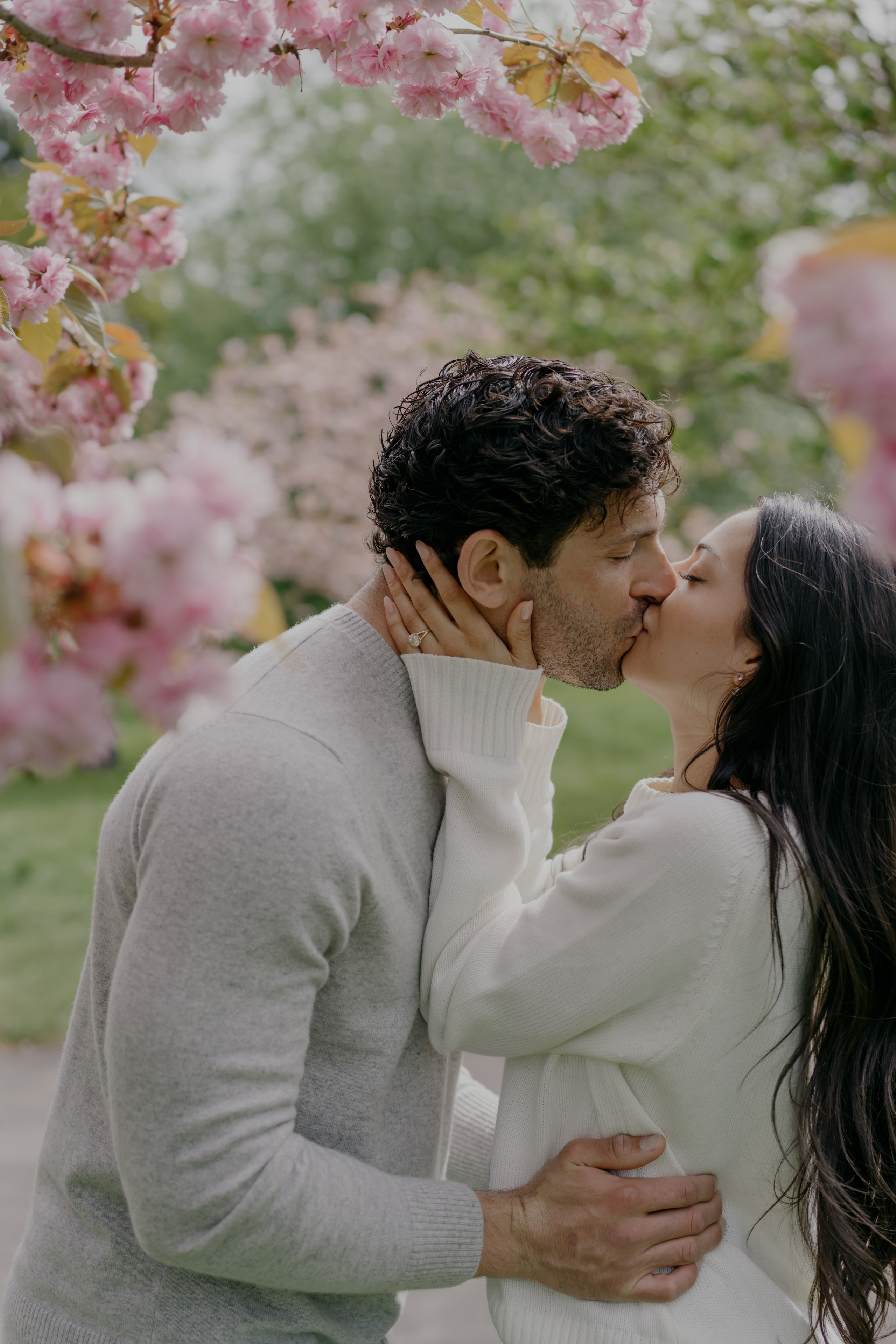 Couple kissing under cherry blossoms during London engagement photoshoot