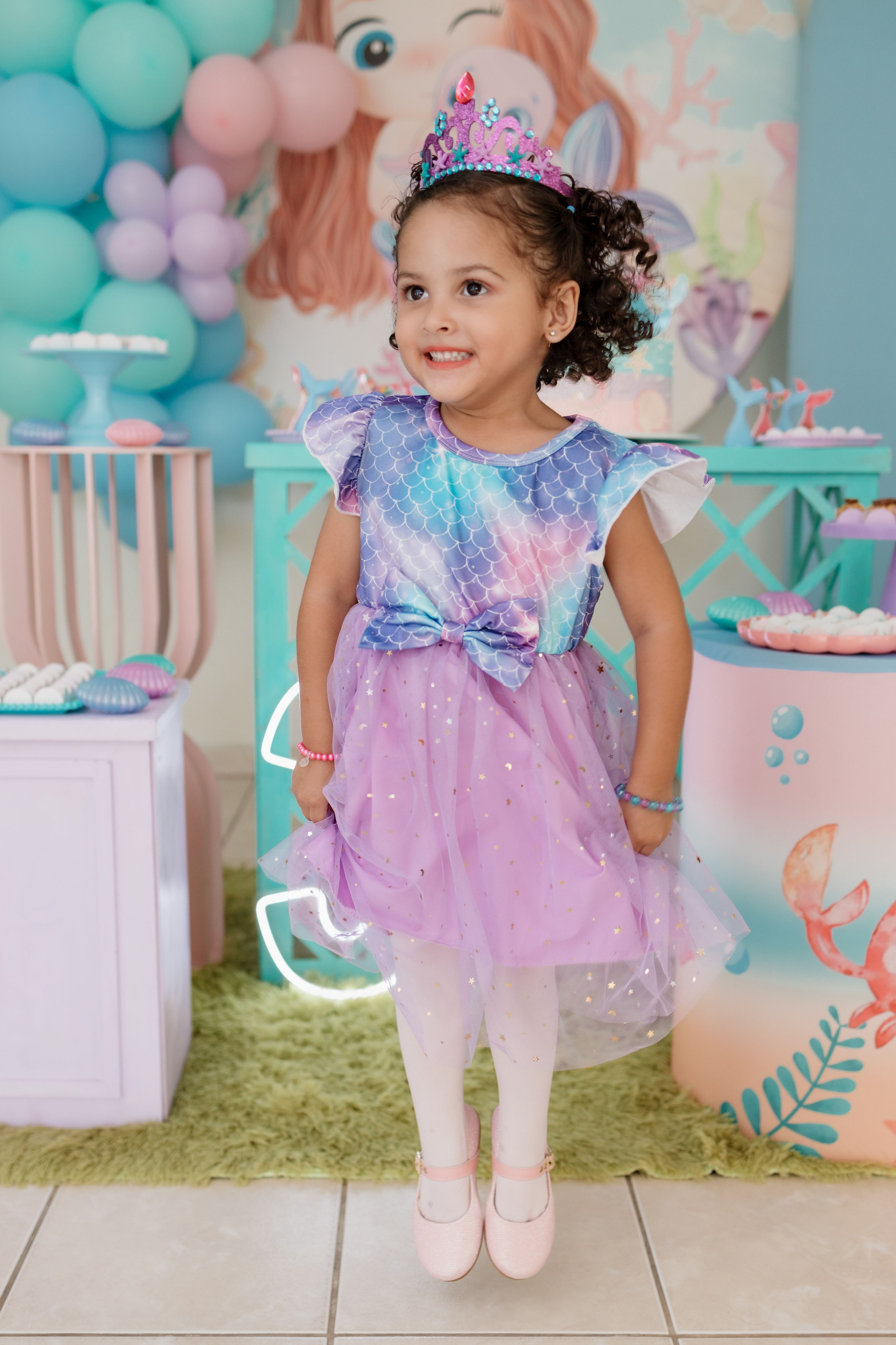 Elisa brincando de bailarina com roupa de sereia em frente a decoração da festa