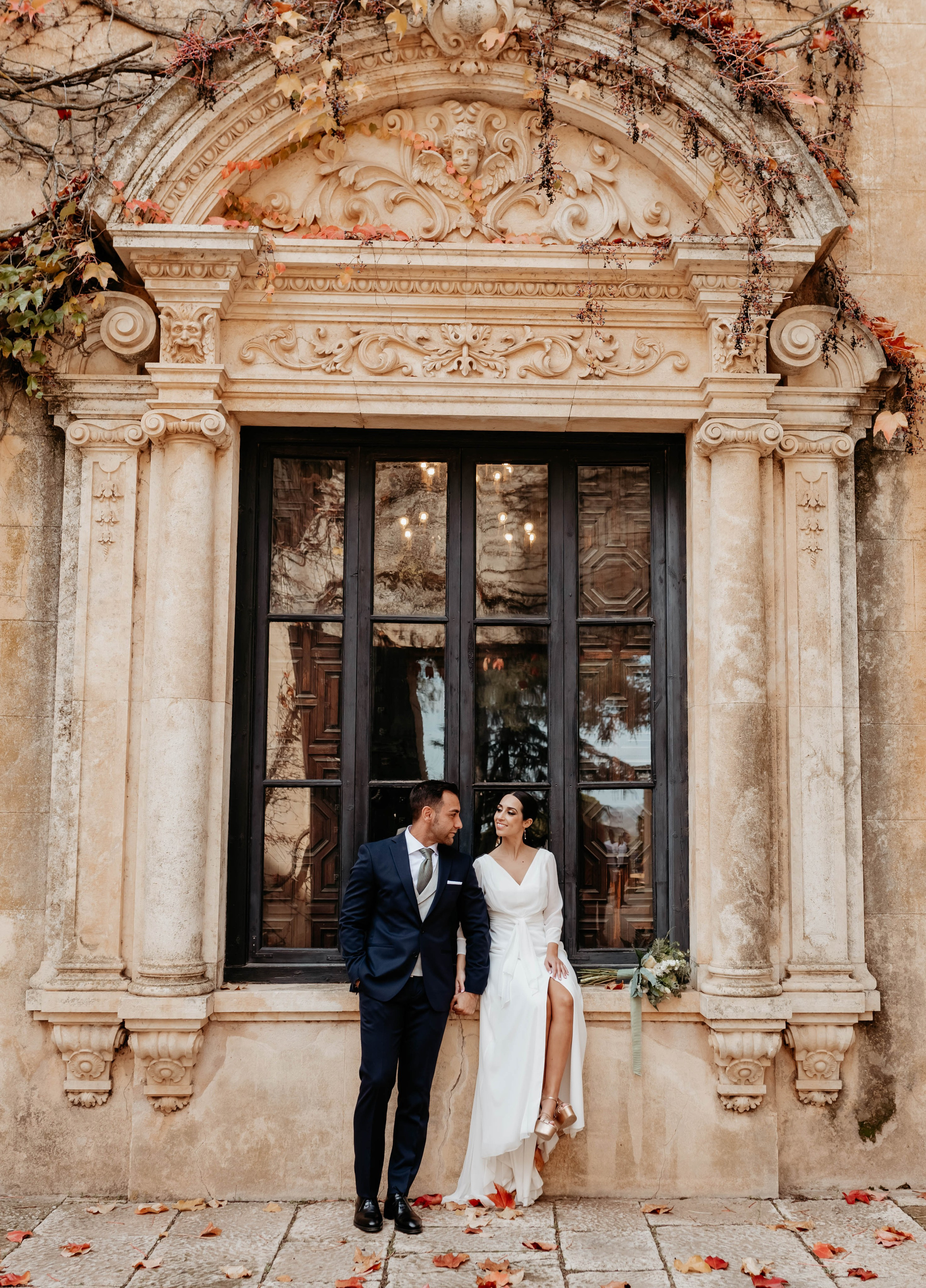 Novios posando en ventana con arquitectura clásica en Finca Torrefiel