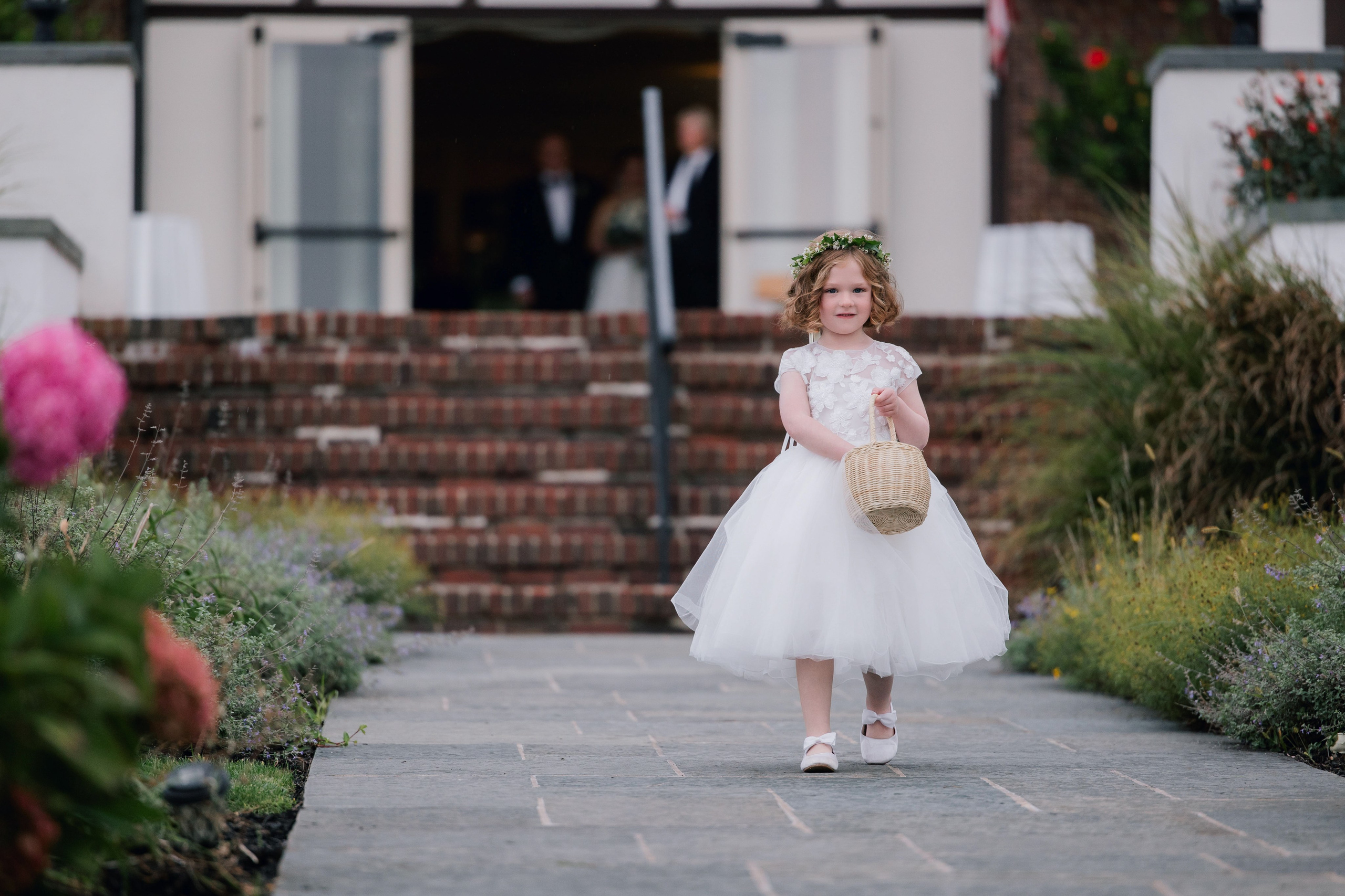 a little girl in a white dress walking down a path