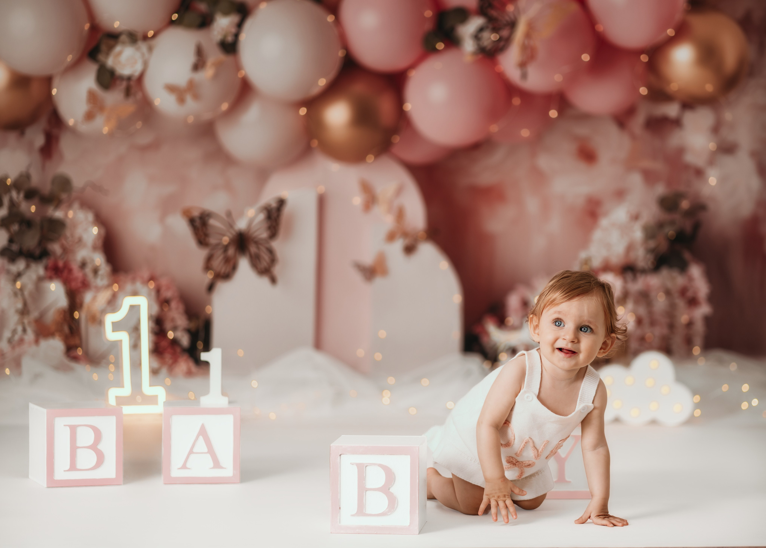 Cake smash fotografisanje devojčice sa tortom u roze dekoraciji leptira